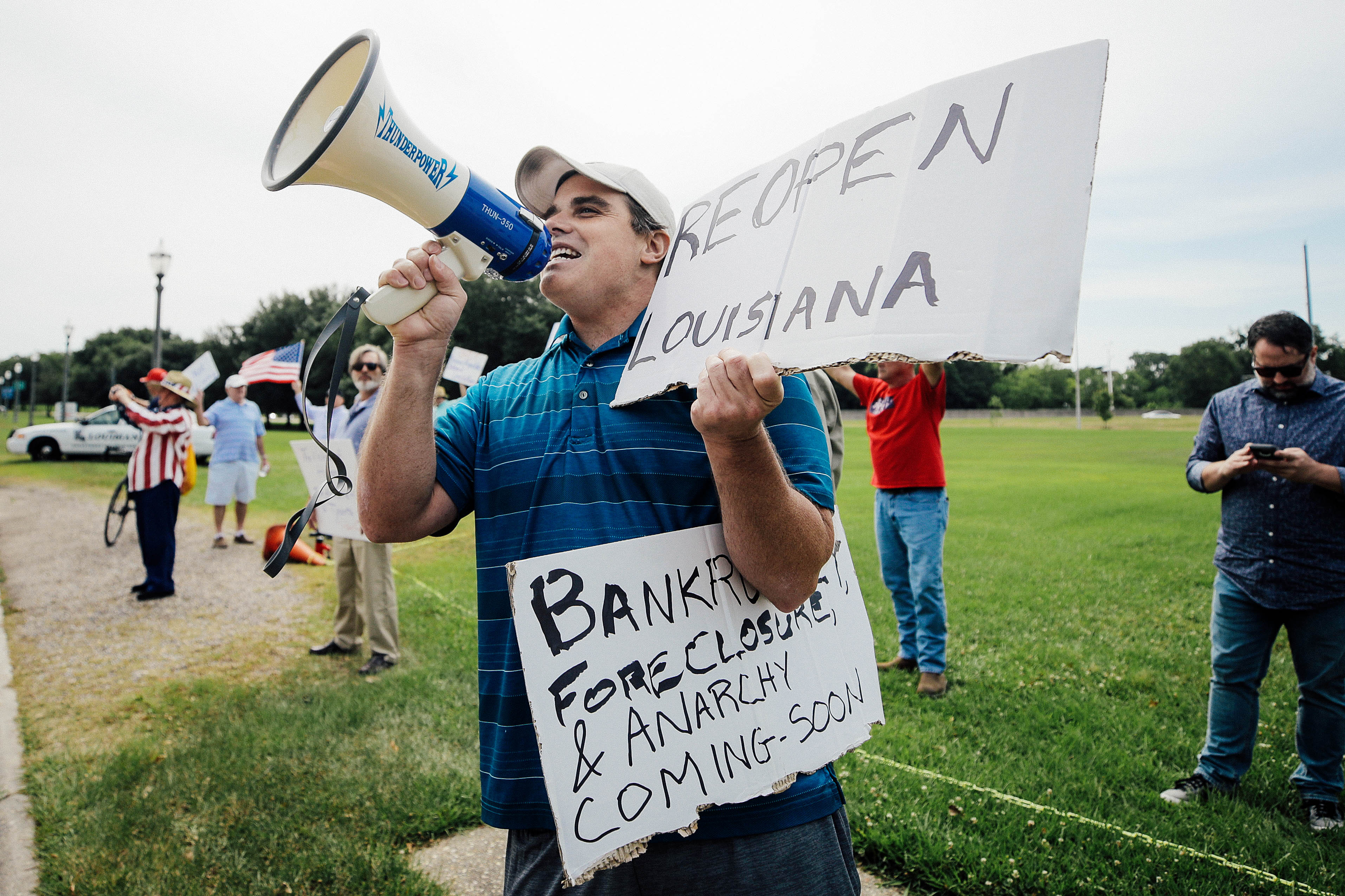 A protester holds a bullhorn and a sign that says, "Reopen Louisiana."