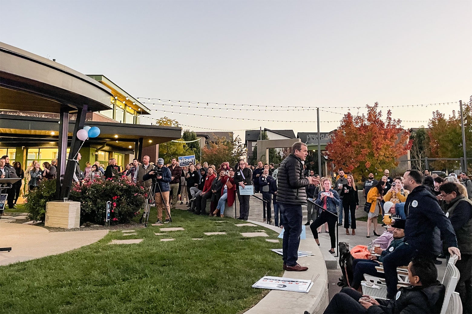 Bennet stands on a ledge outside of a brewery talking to supporters.