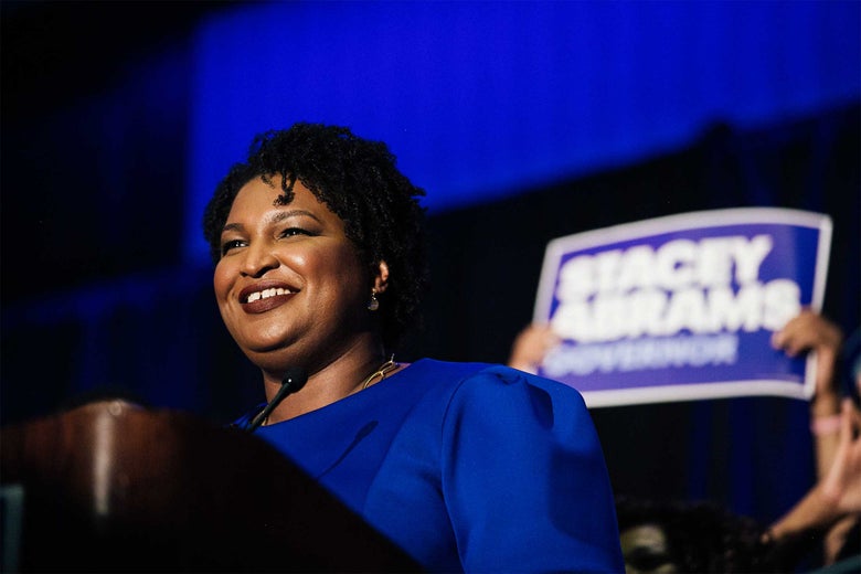 Stacey Abrams smiles from behind a podium.