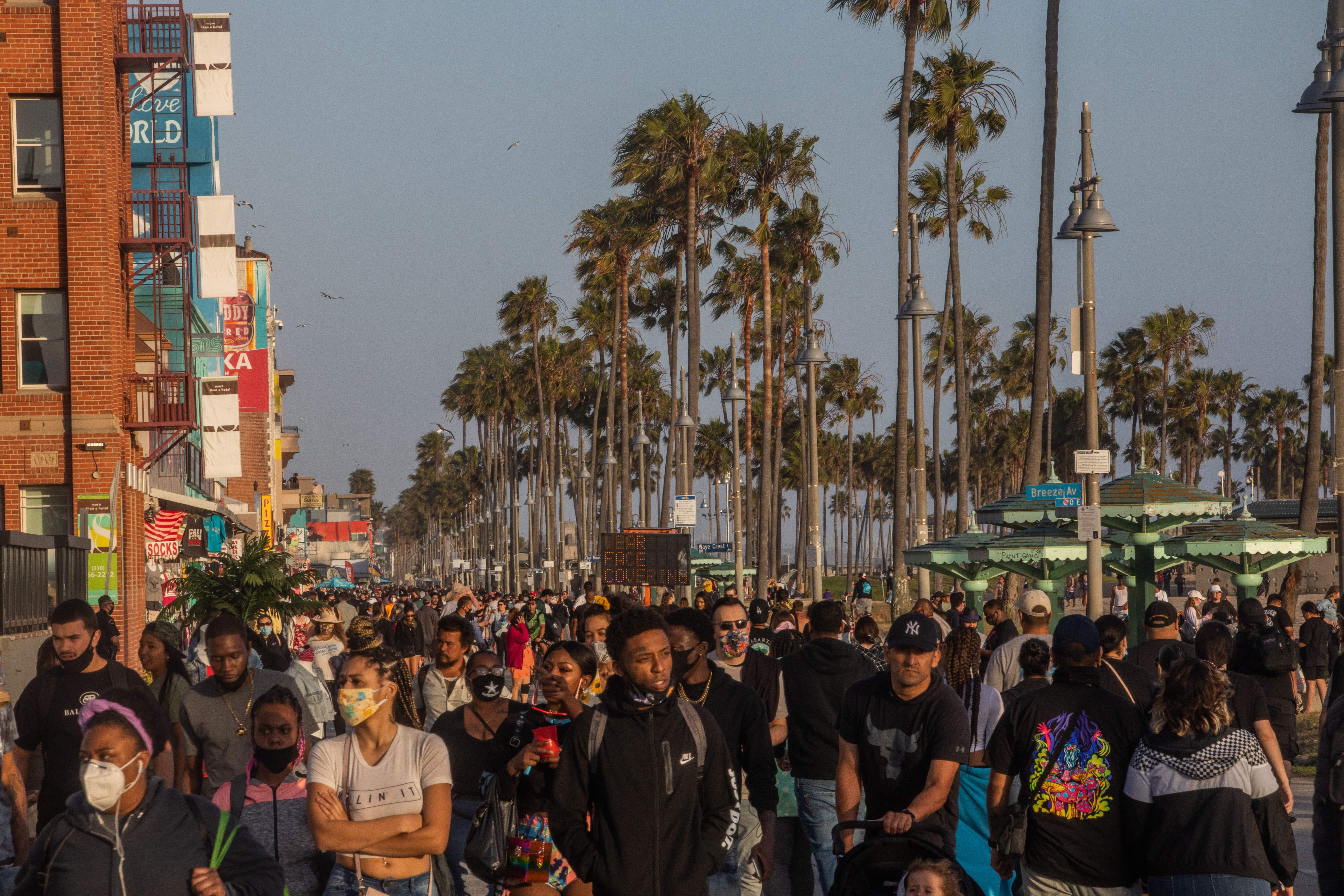 People walk at the boardwalk in Venice Beach during the first day of the Memorial Day holiday weekend amid the novel Coronavirus, COVID-19, pandemic in California on May 23, 2020. 