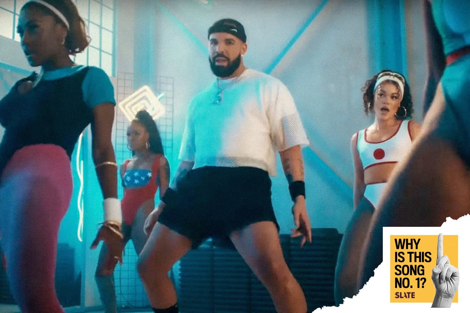 A man thrusts forward in a dance class. He is wearing a white shirt with a gold chain around his neck, black shorts, a black headband, and a black arm band. 