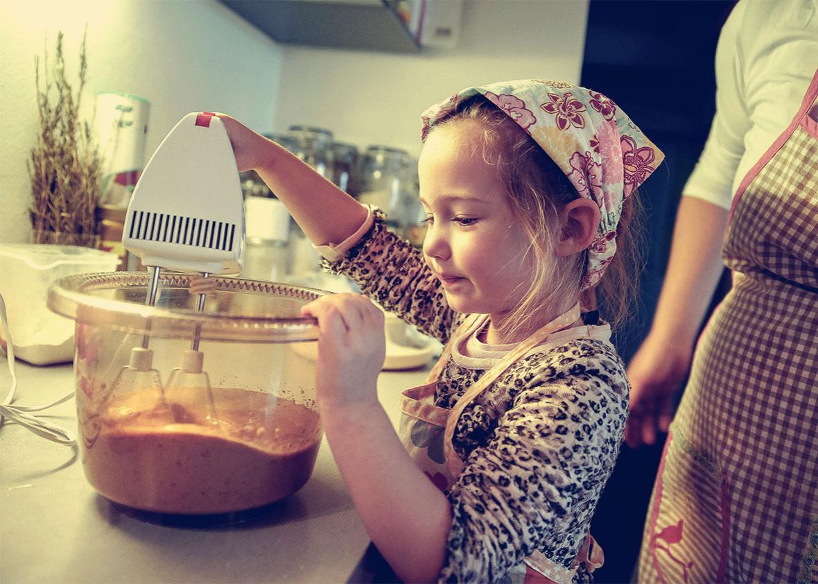 Little girl mixing dough for a birthday cake.