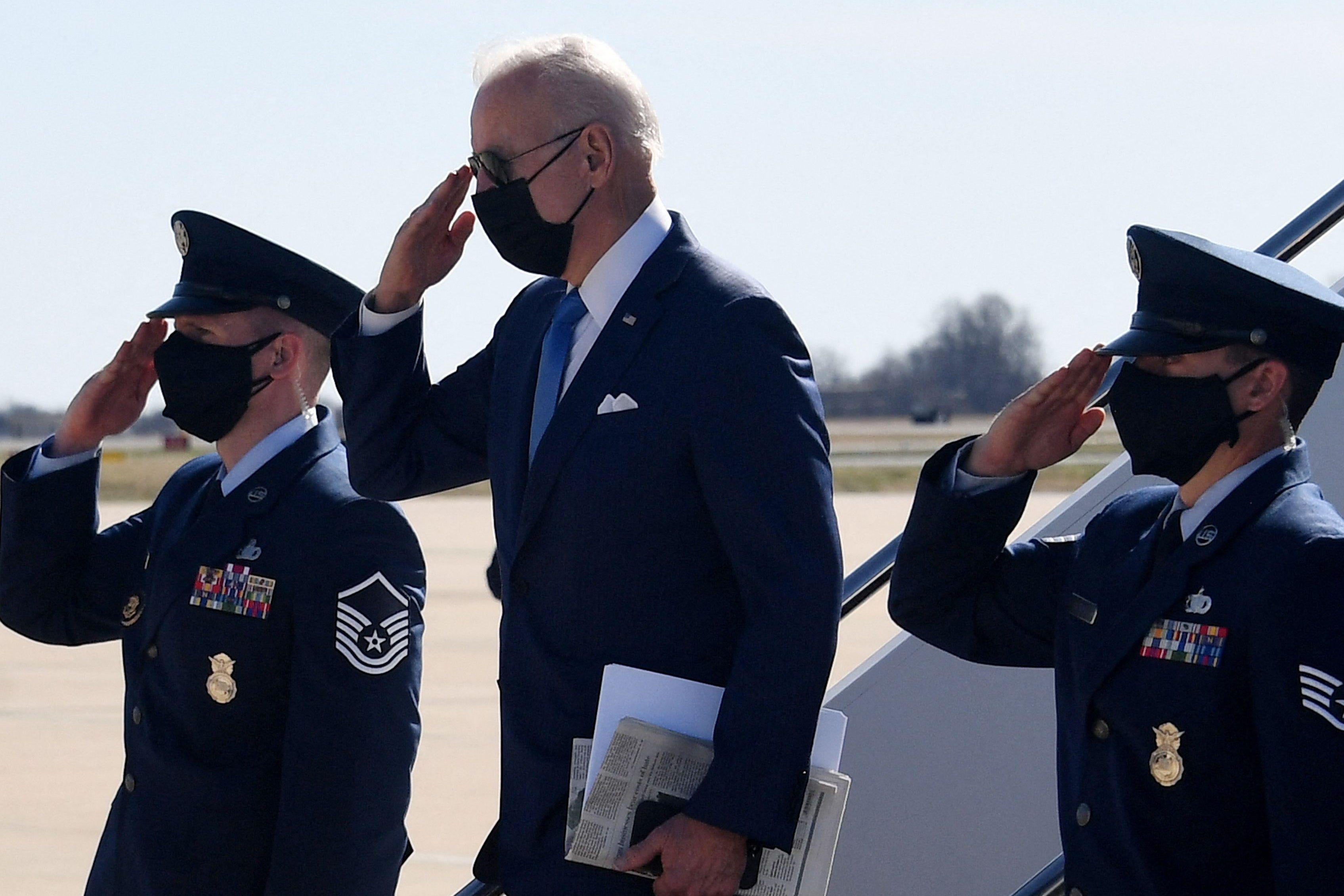 Biden salutes as he disembarks from Air Dorce One, two officers around him saluting, too.