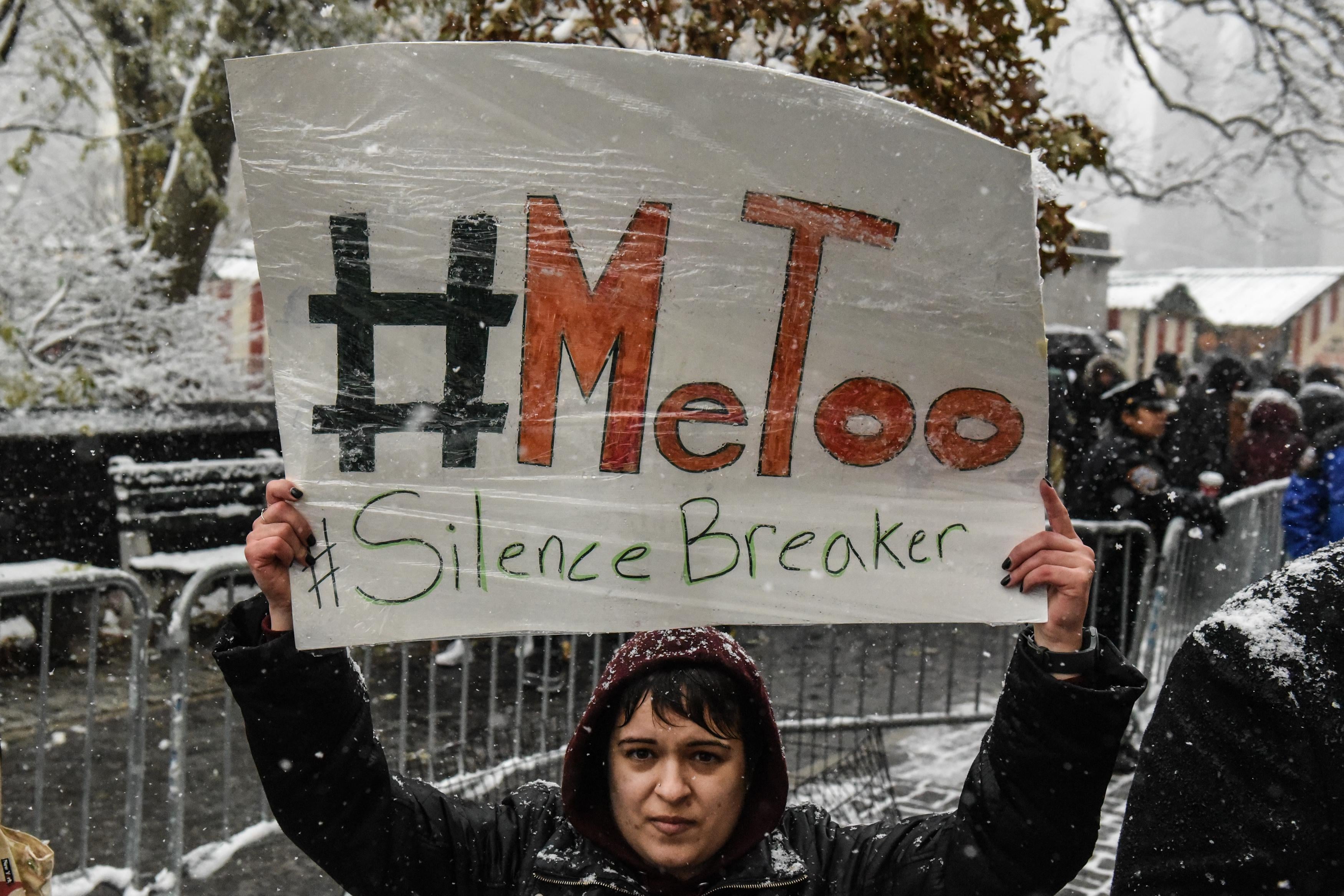A woman holds a sign that says, "#MeToo #SilenceBreaker."
