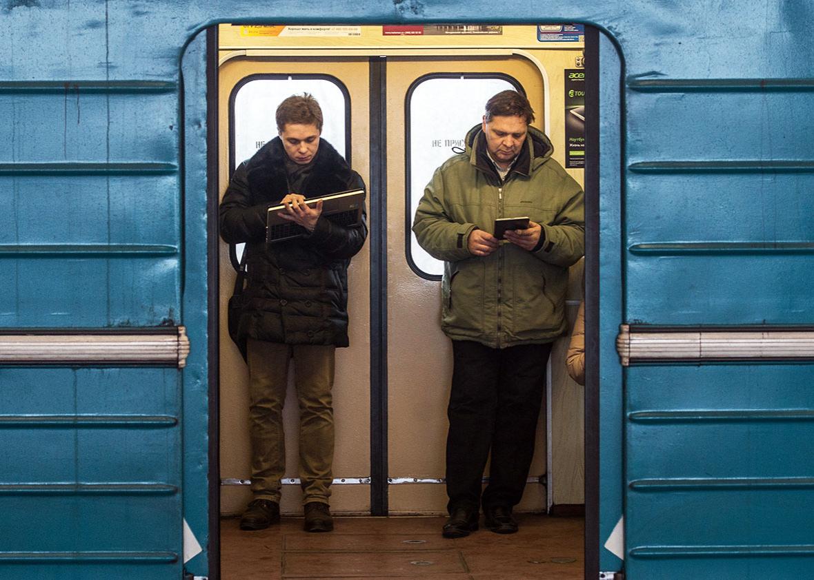 Commuters consult their electronic connected devices inside a train coach in the Moscow Metro, on December 1, 2014.