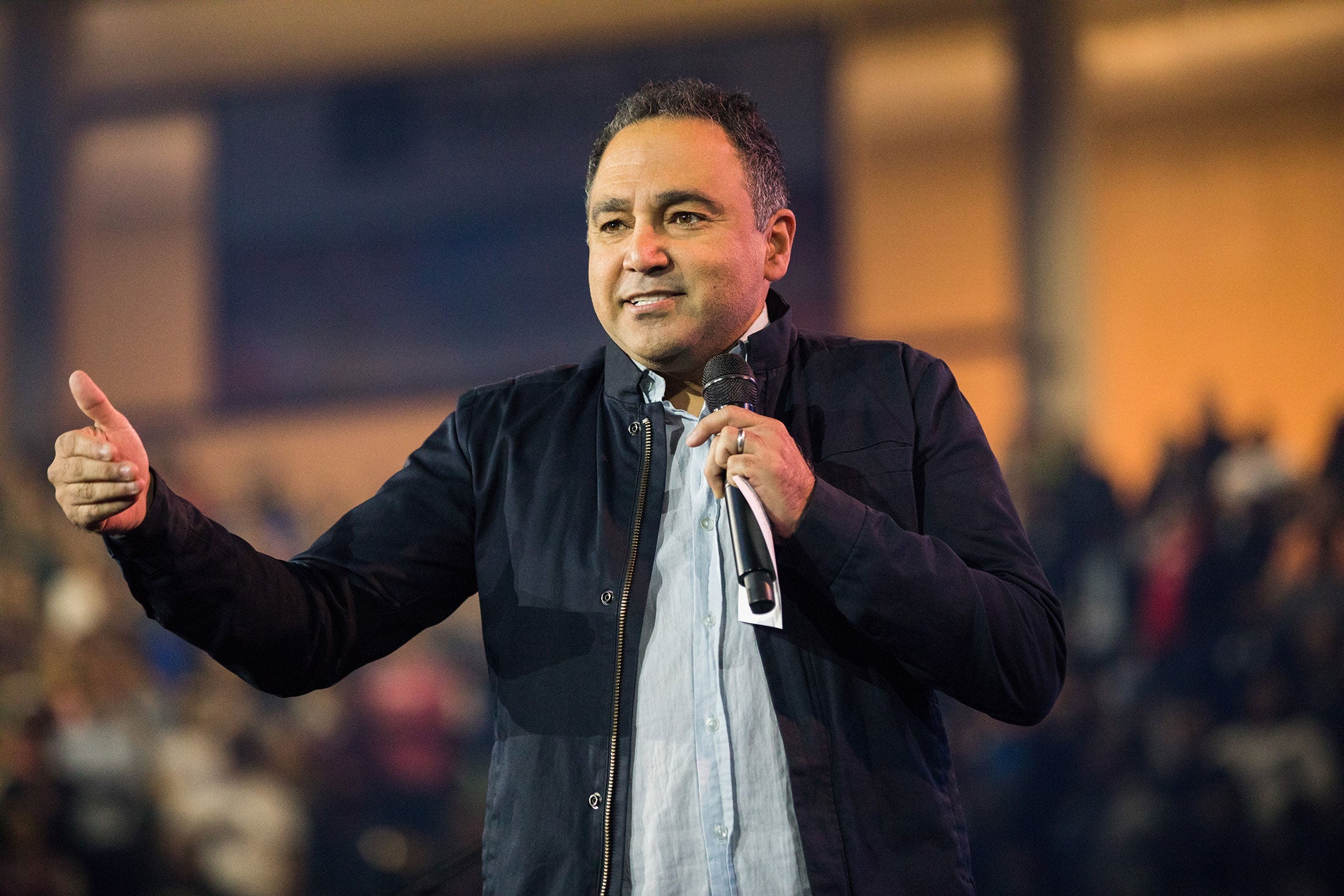 David Nasser holds a mic, giving a speech at Convocation.