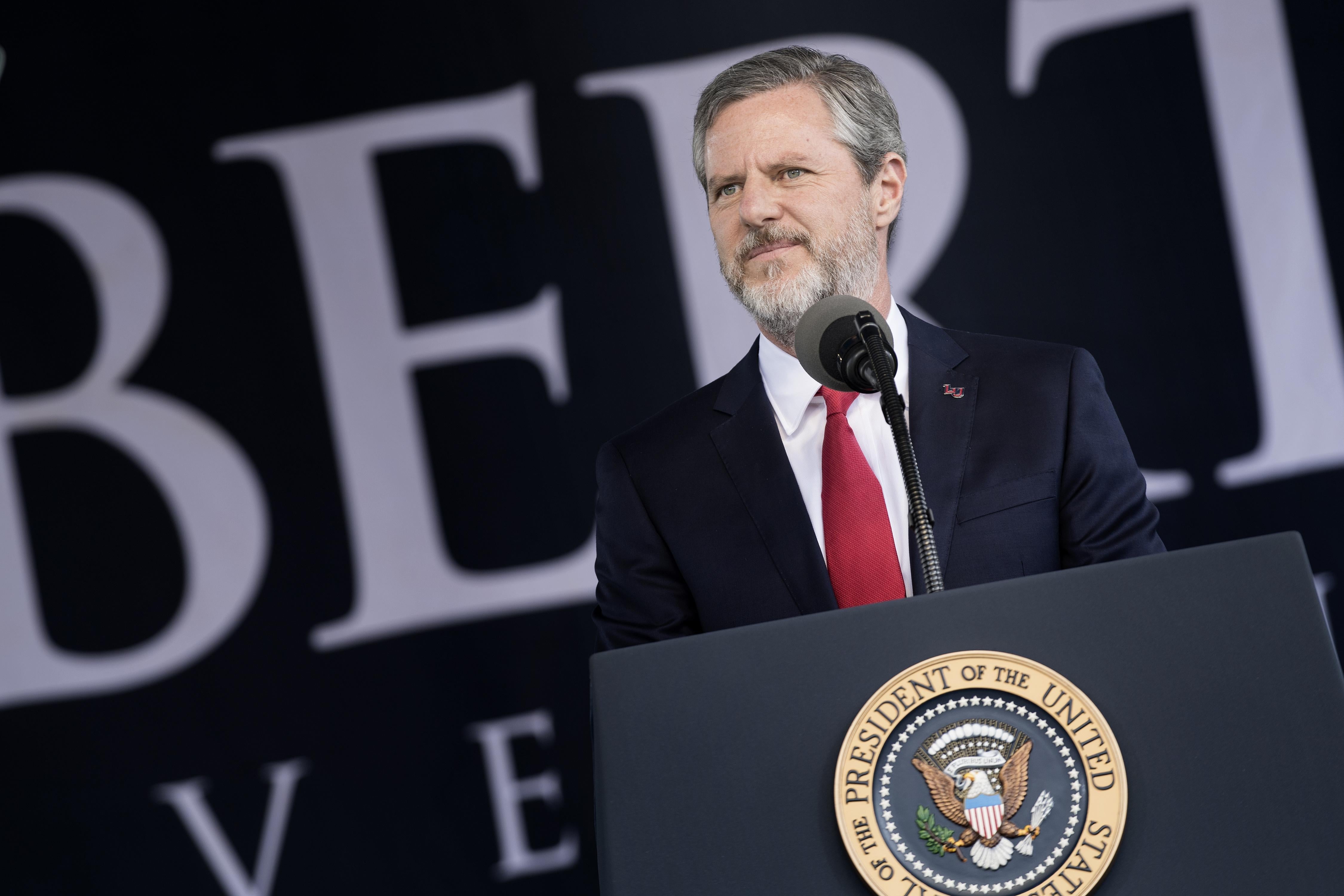 Falwell smiles, standing behind a podium bearing the U.S. presidential seal.