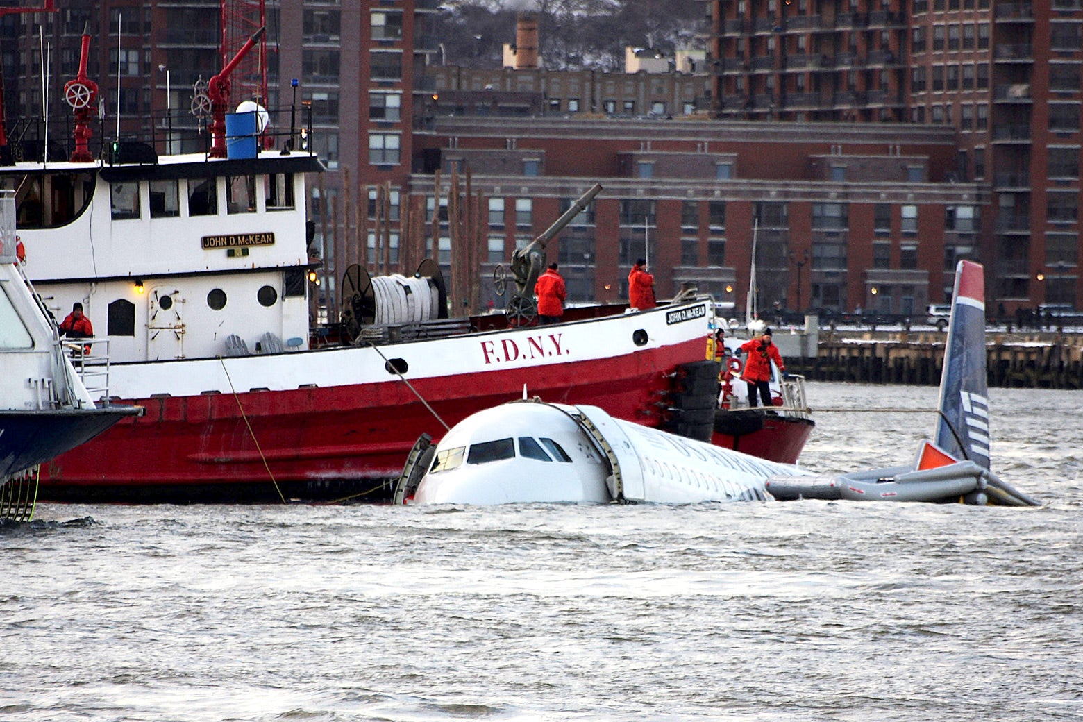 A New York City Fire Department boat floats next to partially submerged plane in the Hudson River.