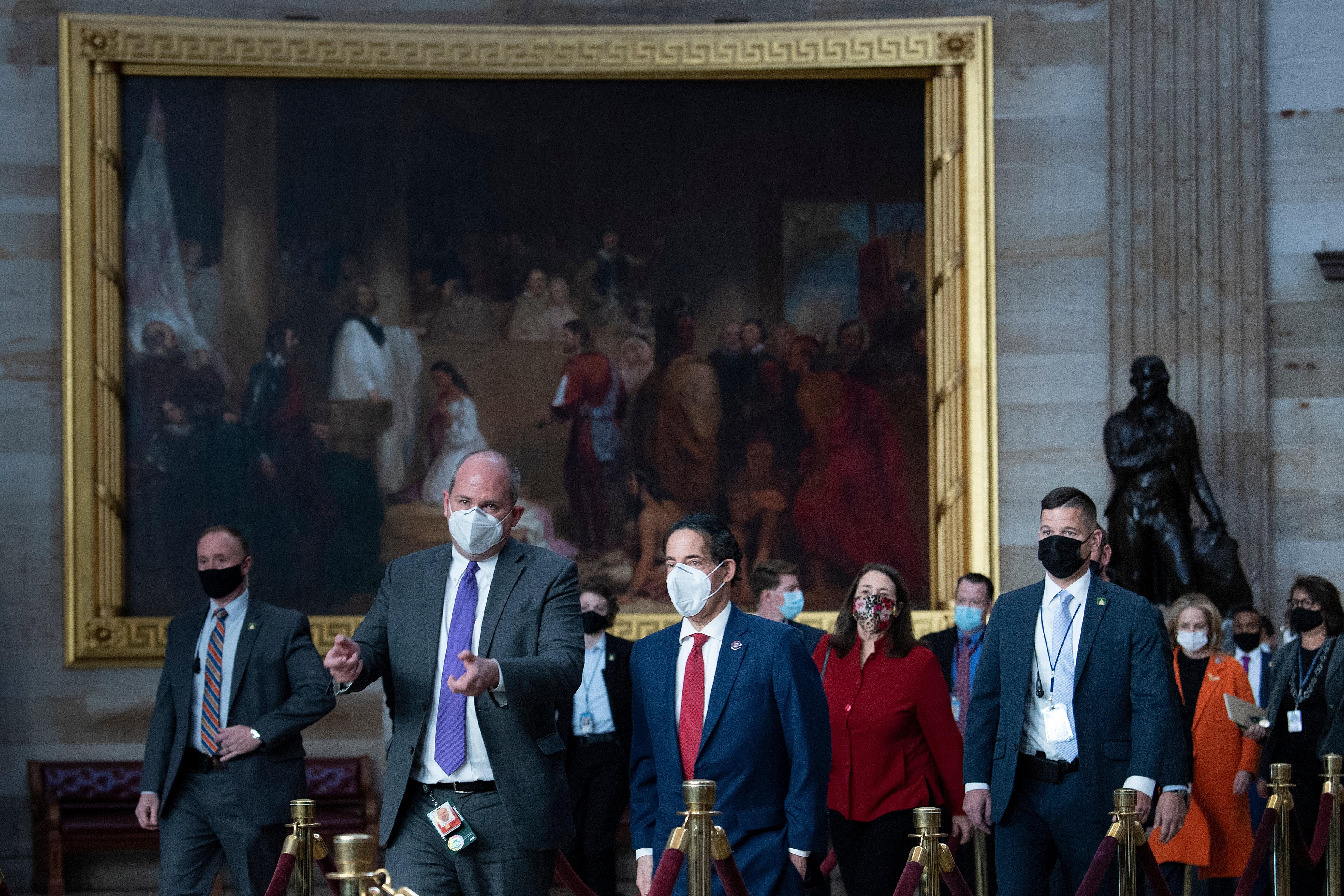 Raskin leads a group of people wearing masks past a large painting on a wall inside the Capitol