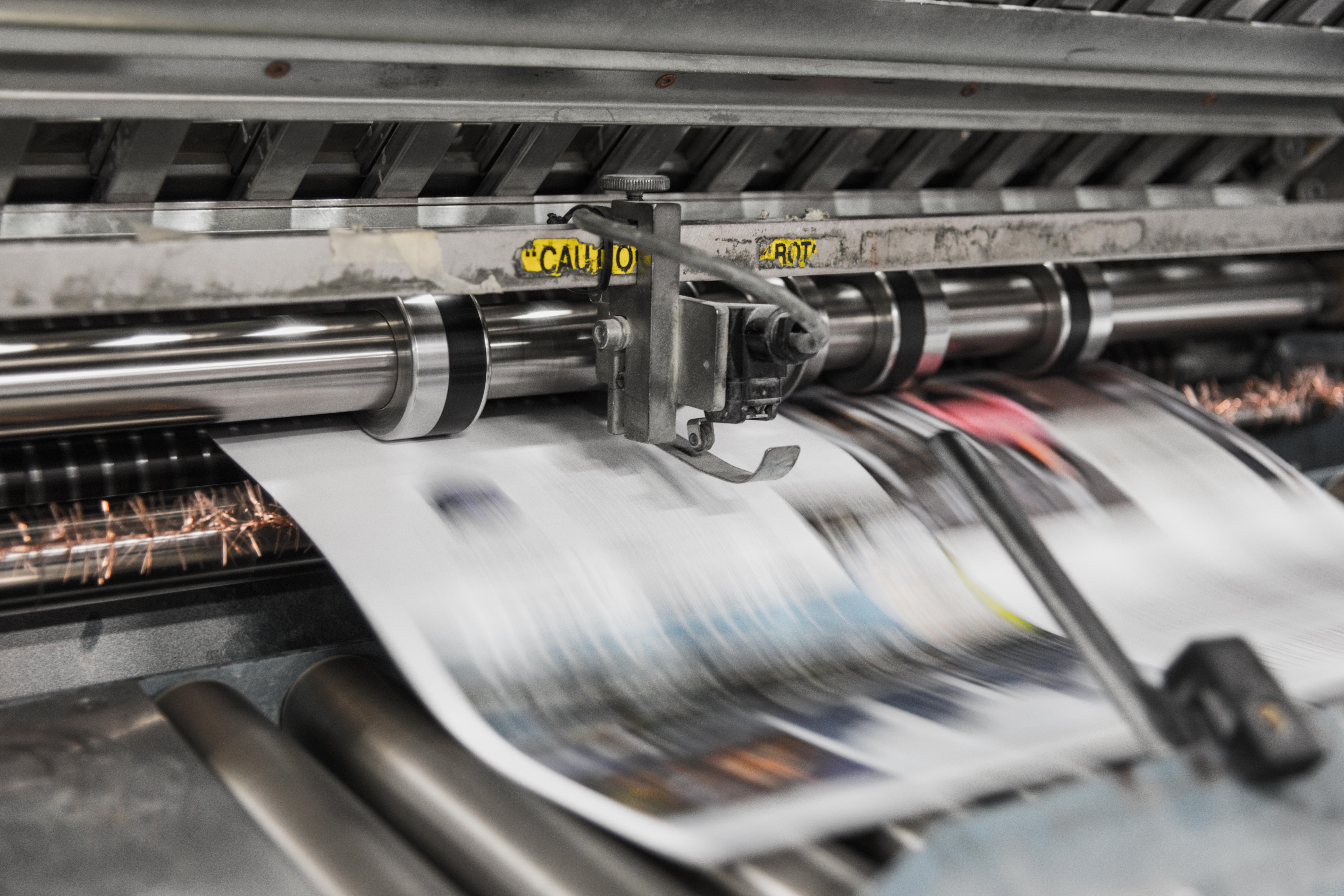A newspaper coming out of a printing press.