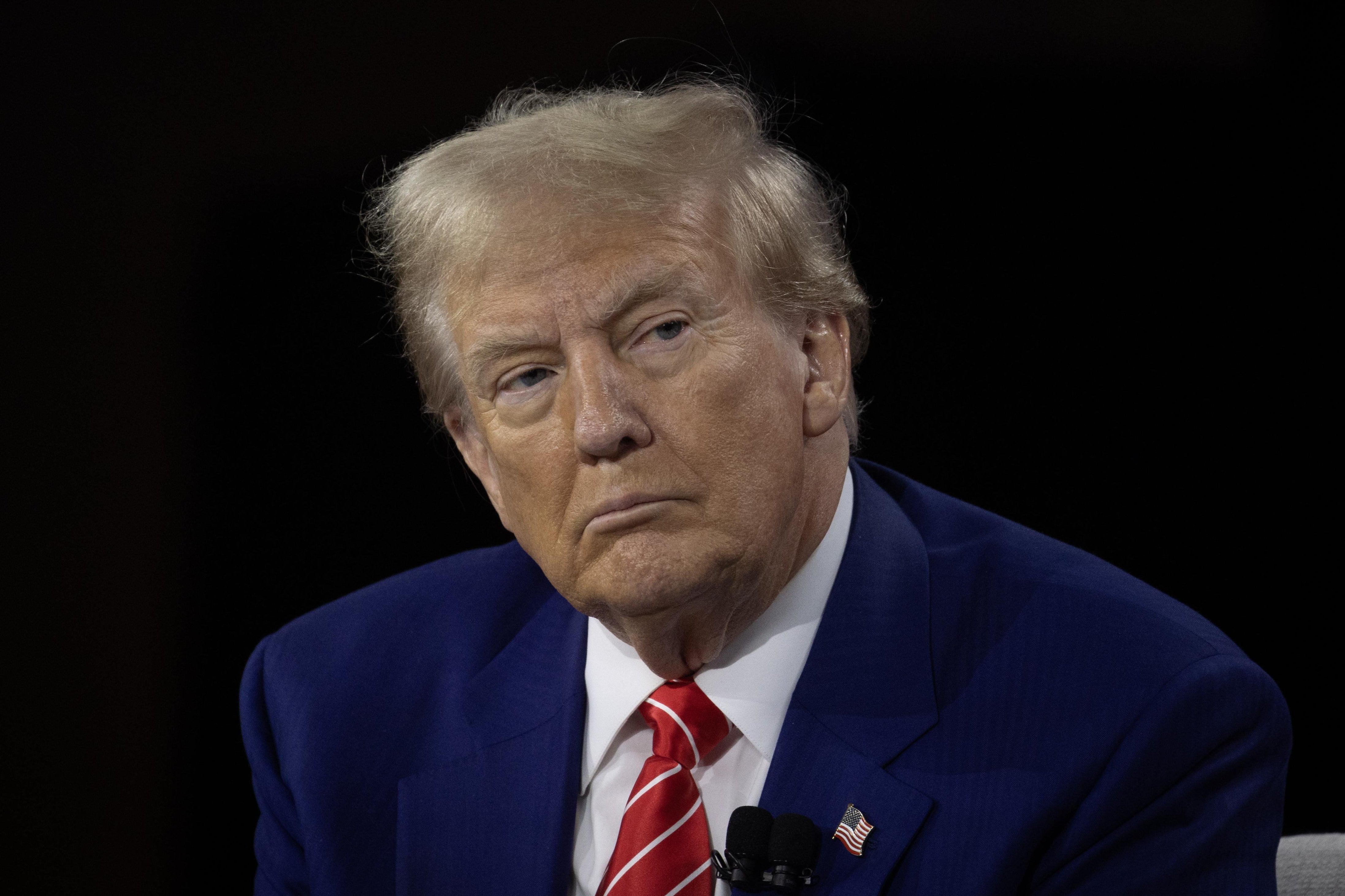 Trump glowers in front of a black background.