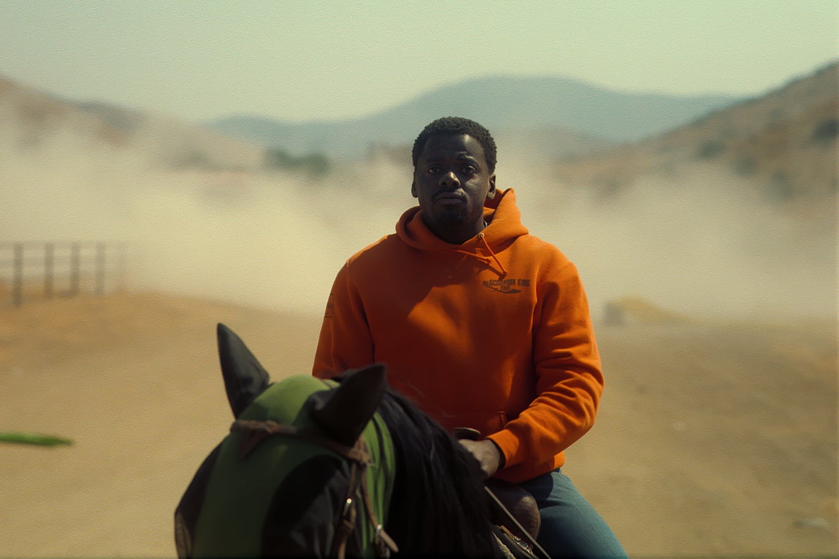 A somber Daniel Kaluuya sits atop a strangely hooded horse in front of an arid, dusty Soutwestern landscape. He wears a hoodie that if you look closely says "Scorpion King," as if the logo for the old movie.