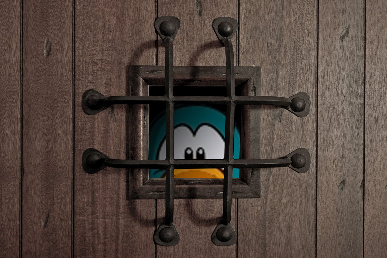 A bright turquoise cartoon penguin peers out from a small, bar-covered hole in a wooden door.