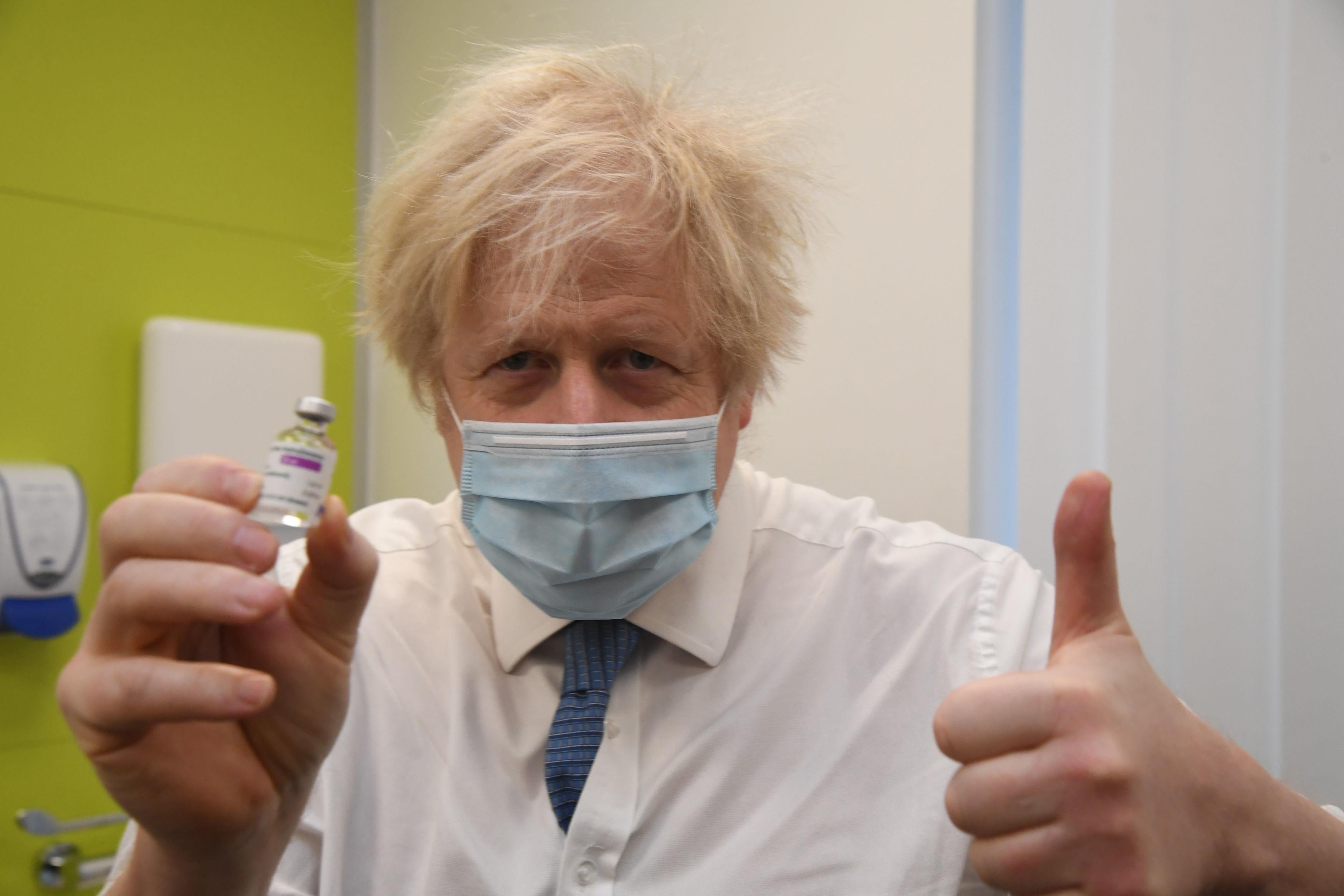 Boris Johnson gives a thumbs-up and holds up a vial of the AstraZeneca/Oxford COVID-19 vaccine.