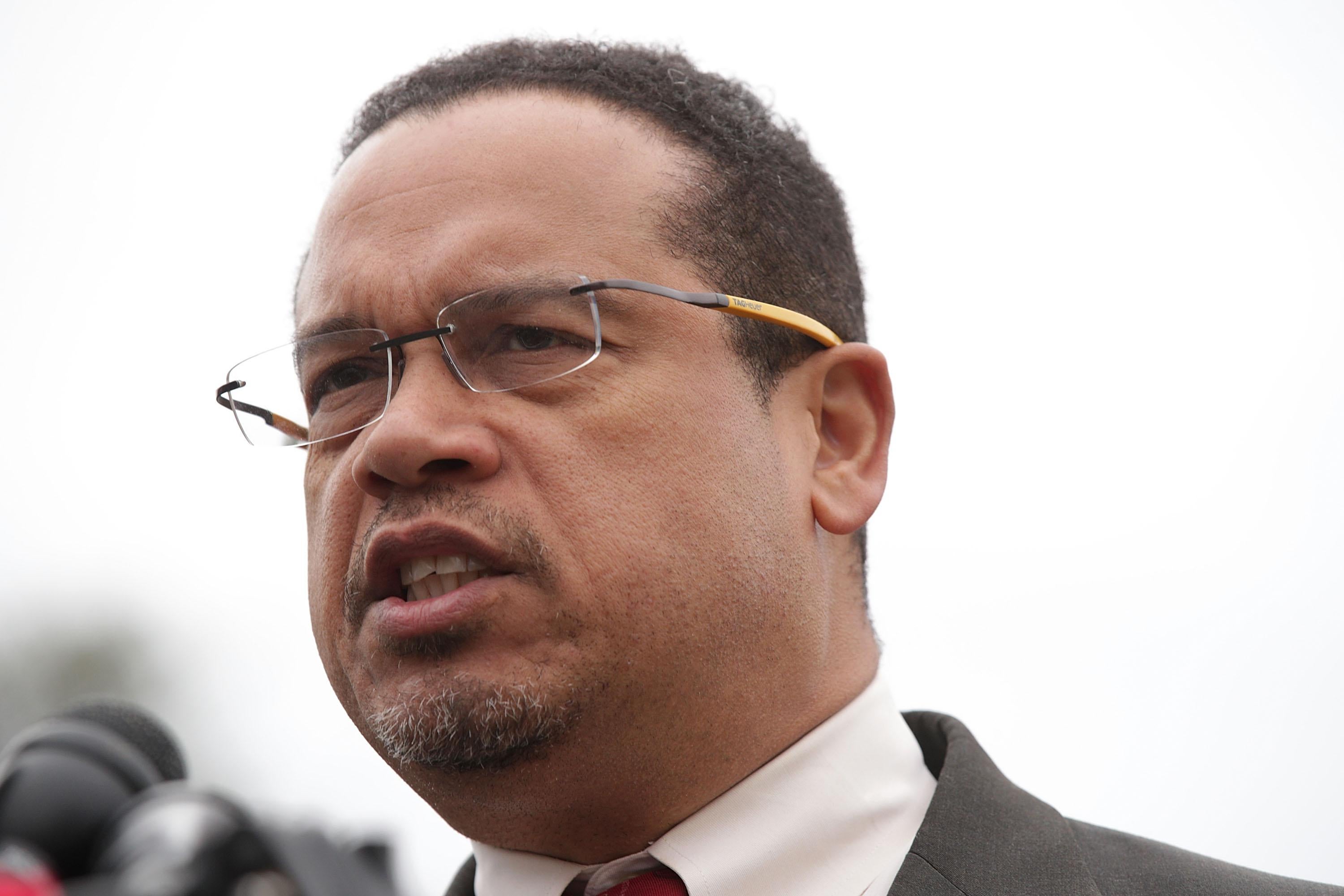 Keith Ellison speaks at a podium with microphones outside.