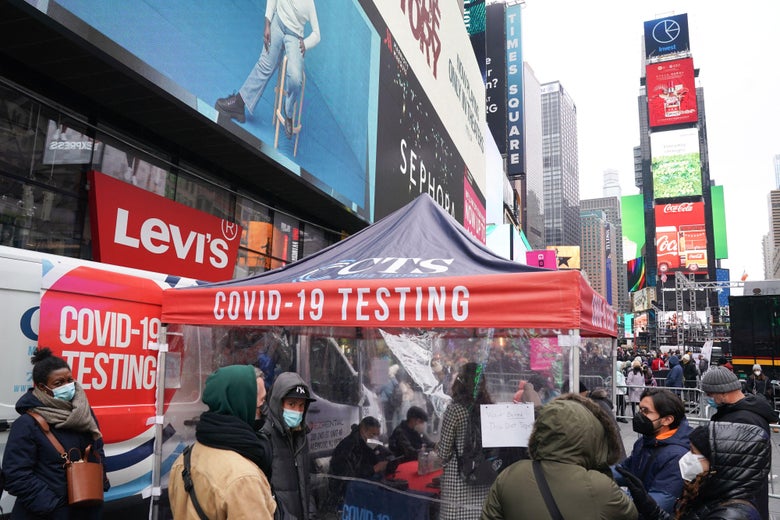 People stand in line near a tent that says COVID-19 TESTING.