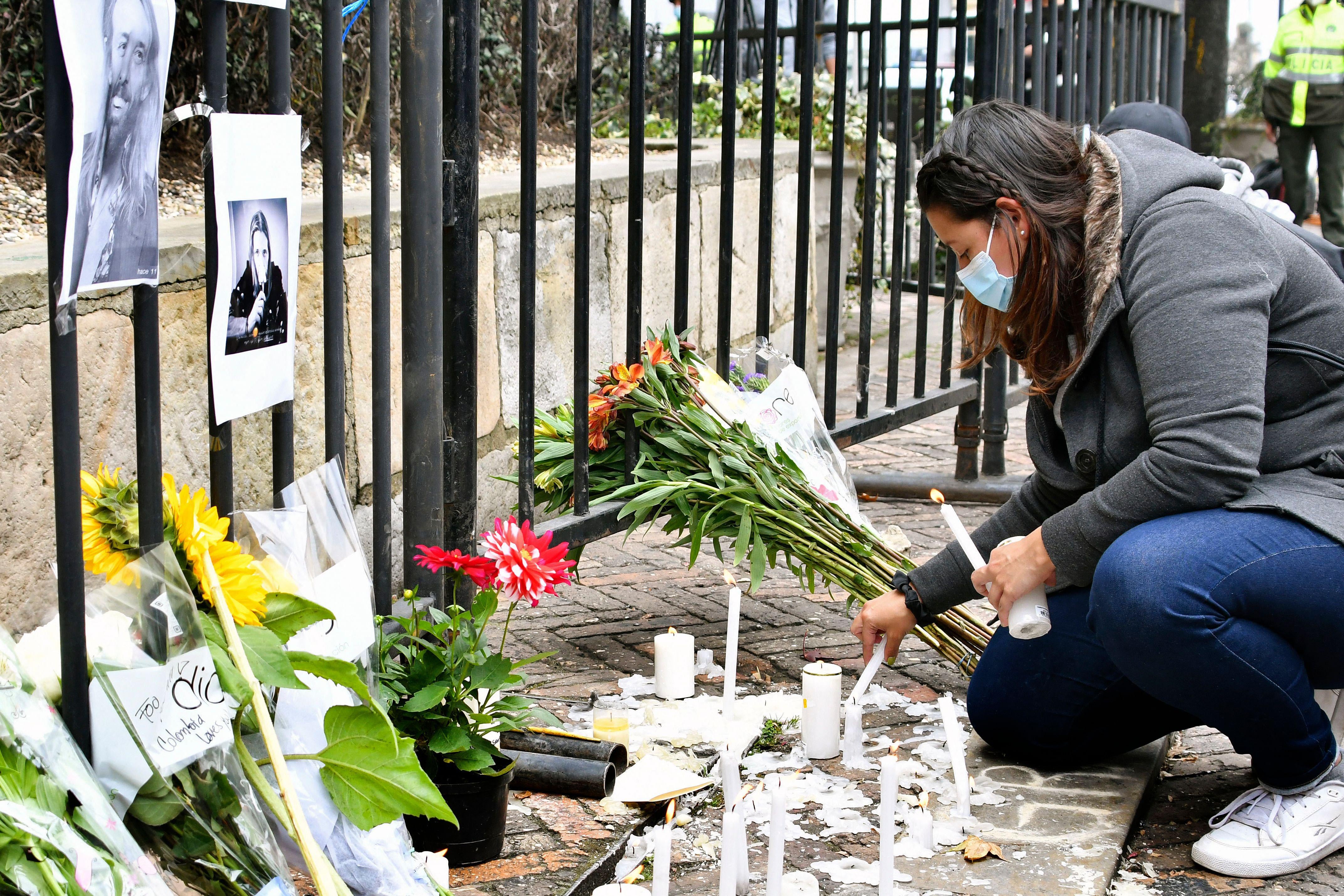 A fan lights a candle outside of the hotel where Foo Fighters' drummer Taylor Hawkins died, on March 26, 2022 in Bogotá.