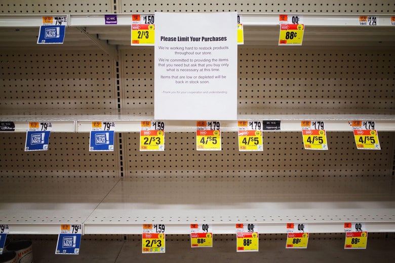 A message that says "Please limit your purchases" is posted on empty shelves for canned goods in a Giant supermarket.
