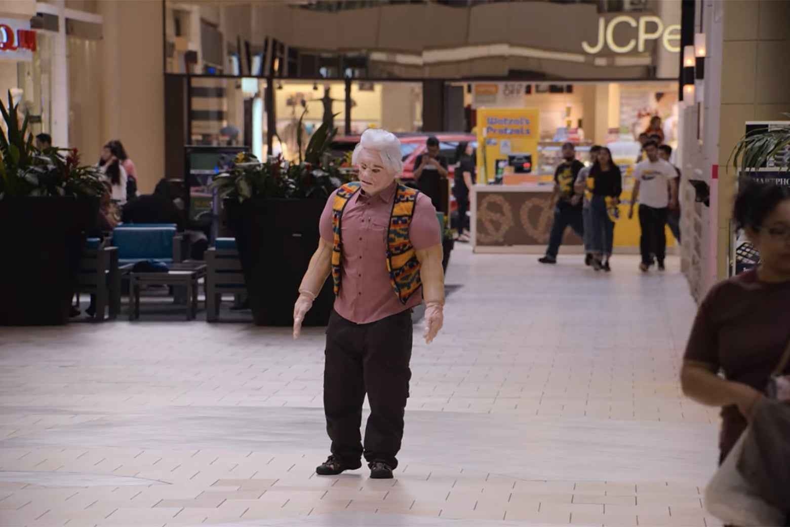 A man in an ill-fitting body suit in the middle of a mall.