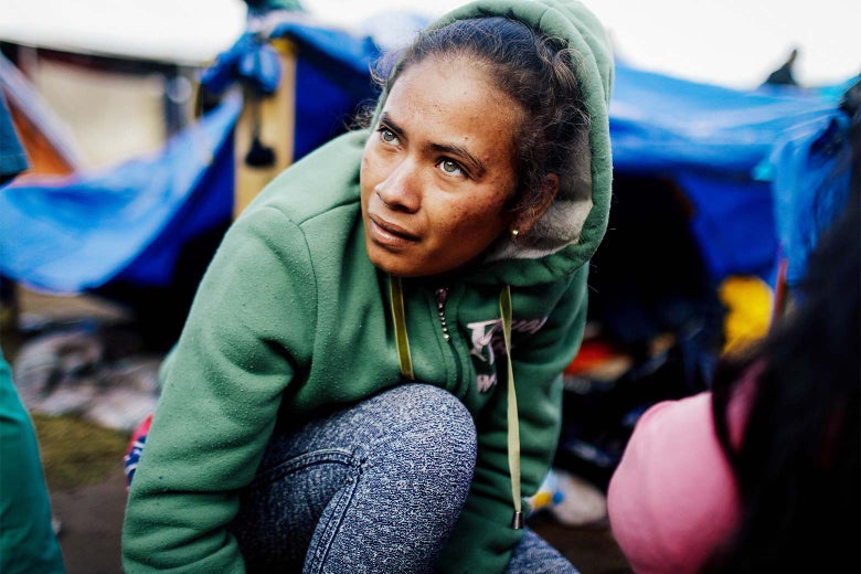 A Honduran woman crouches and looks upward at the sky.