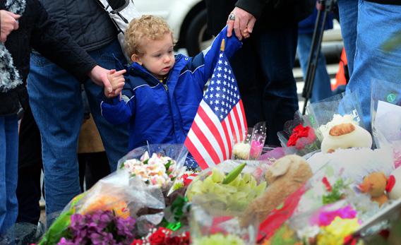 People pay their respects at a makeshift shrine to the victims of an elementary school shooting in Newtown, Connecticut, on Monday.