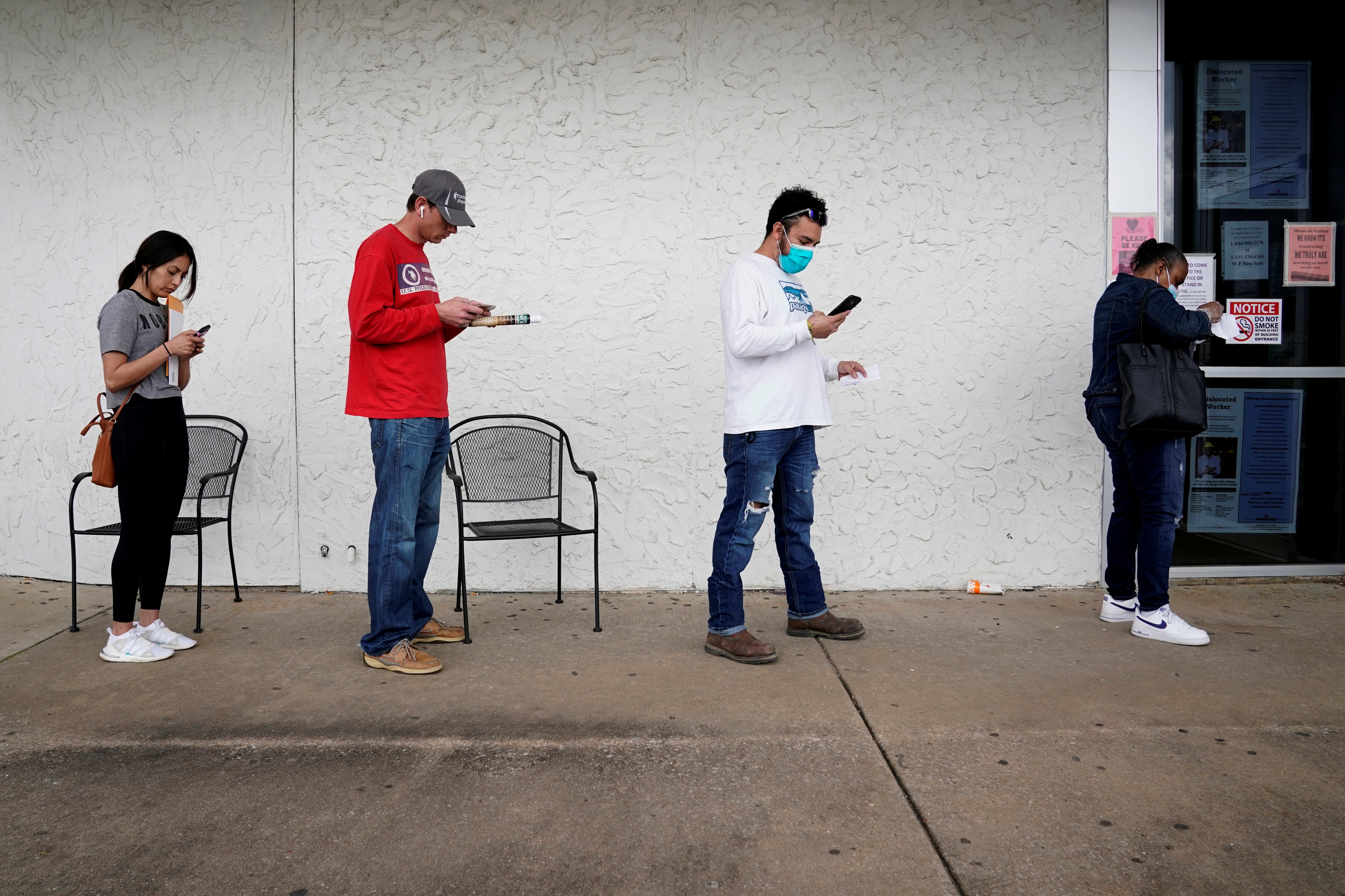 Four Americans wait in a socially distanced line to collect unemployment benefits.