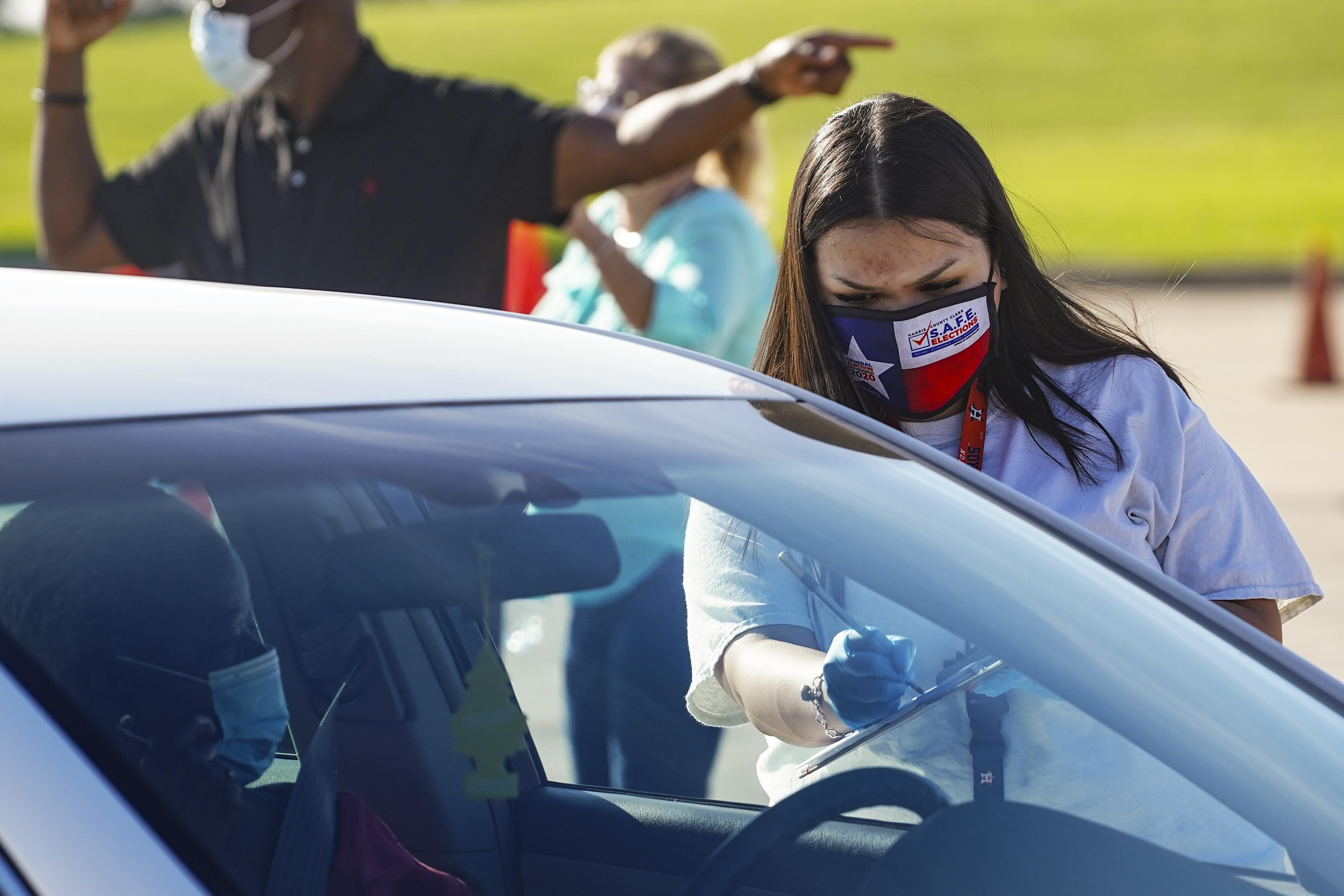 An election worker accepts mail in ballot from a voter at drive-through mail ballot drop off site at NRG Stadium on Oct. 7, 2020 in Houston, Texas. 