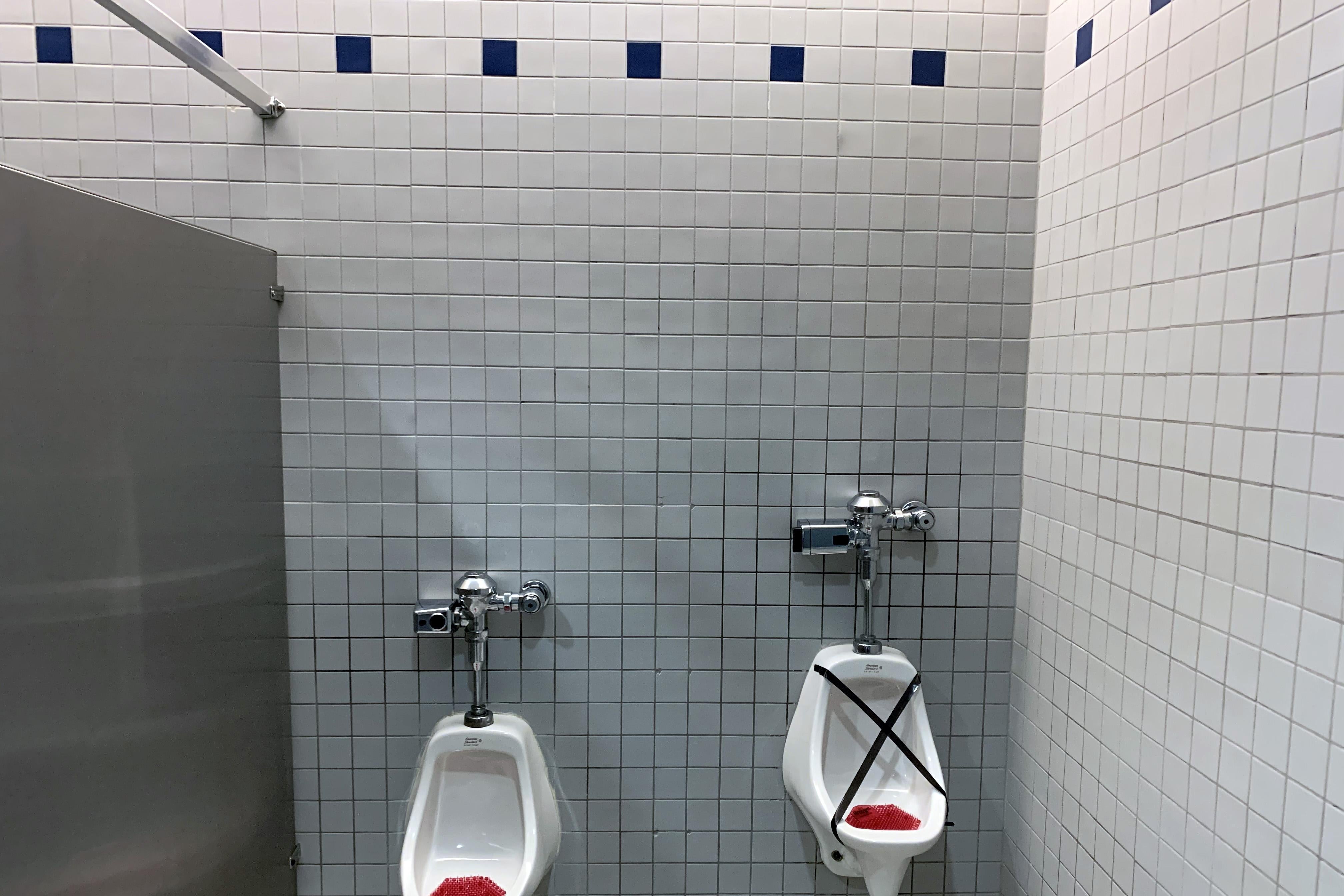 Two urinals, one taped off for social distancing.