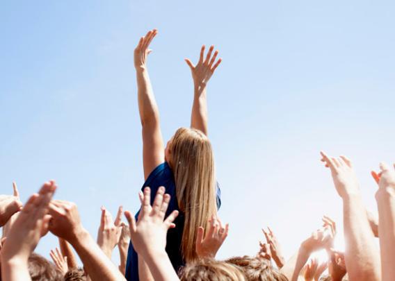 Woman with arms raised above crowd