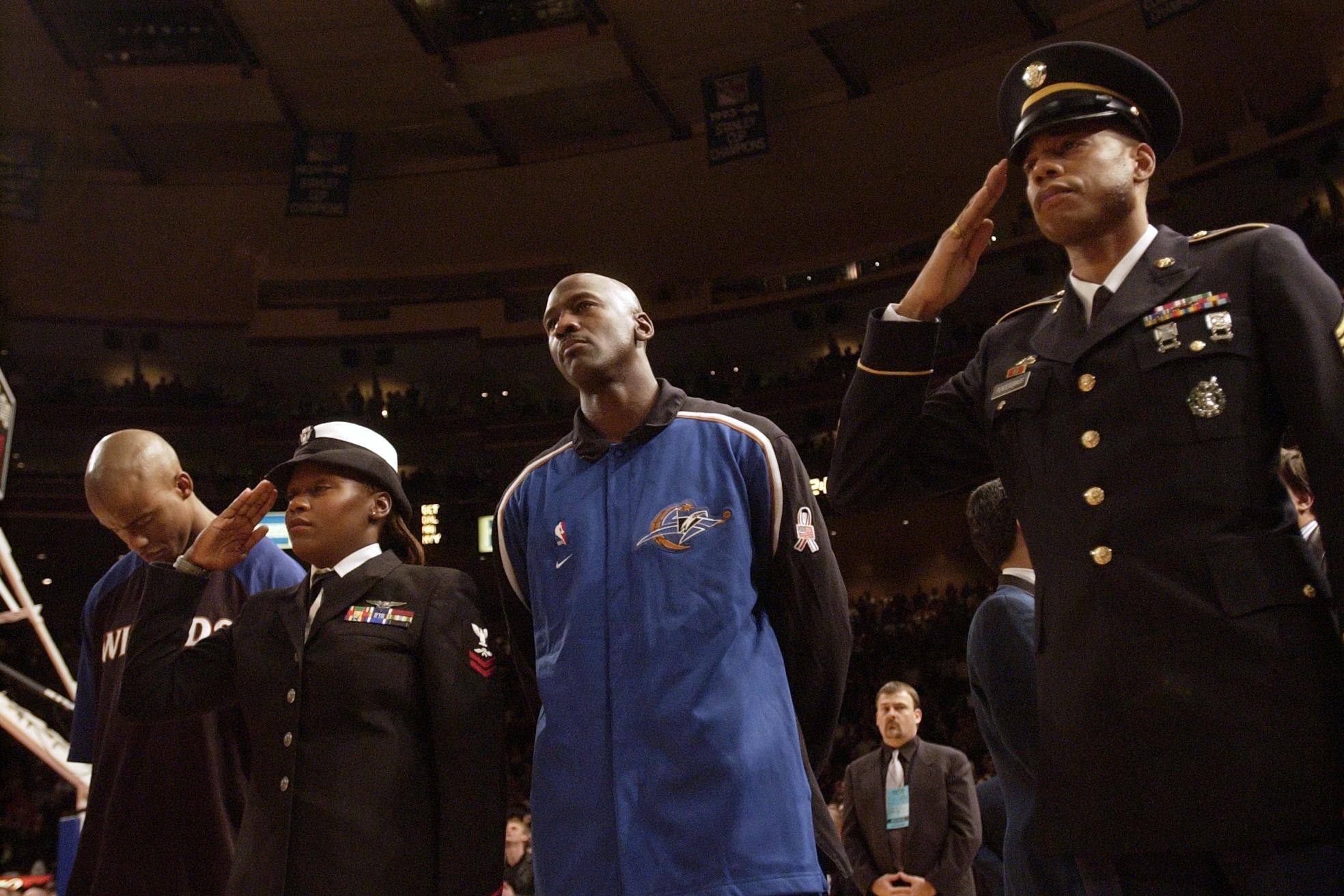 Michael Jordan stands between two members of the military during the national anthem.