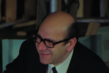 A mostly bald man wearing glasses and smiling