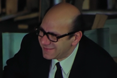 A mostly bald man wearing glasses and smiling