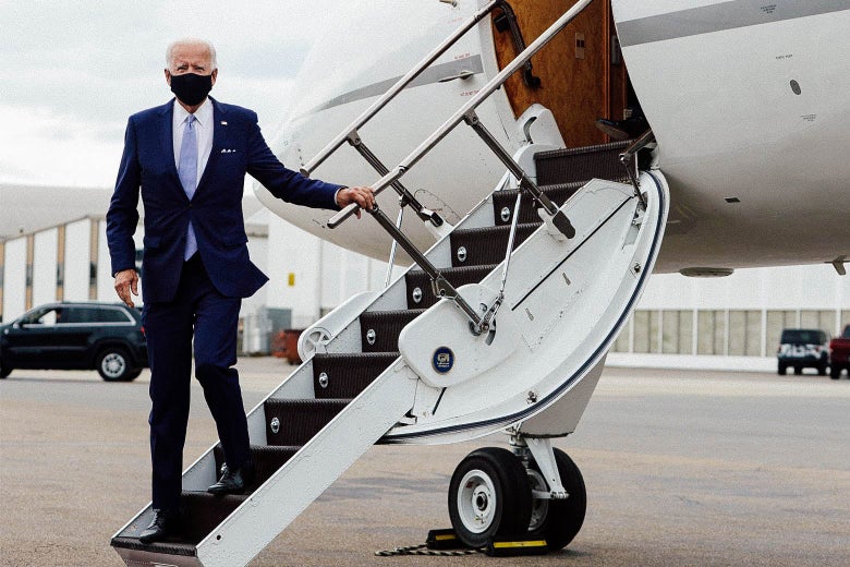 Biden, getting off a plane, stands on the stairs and holds the railing