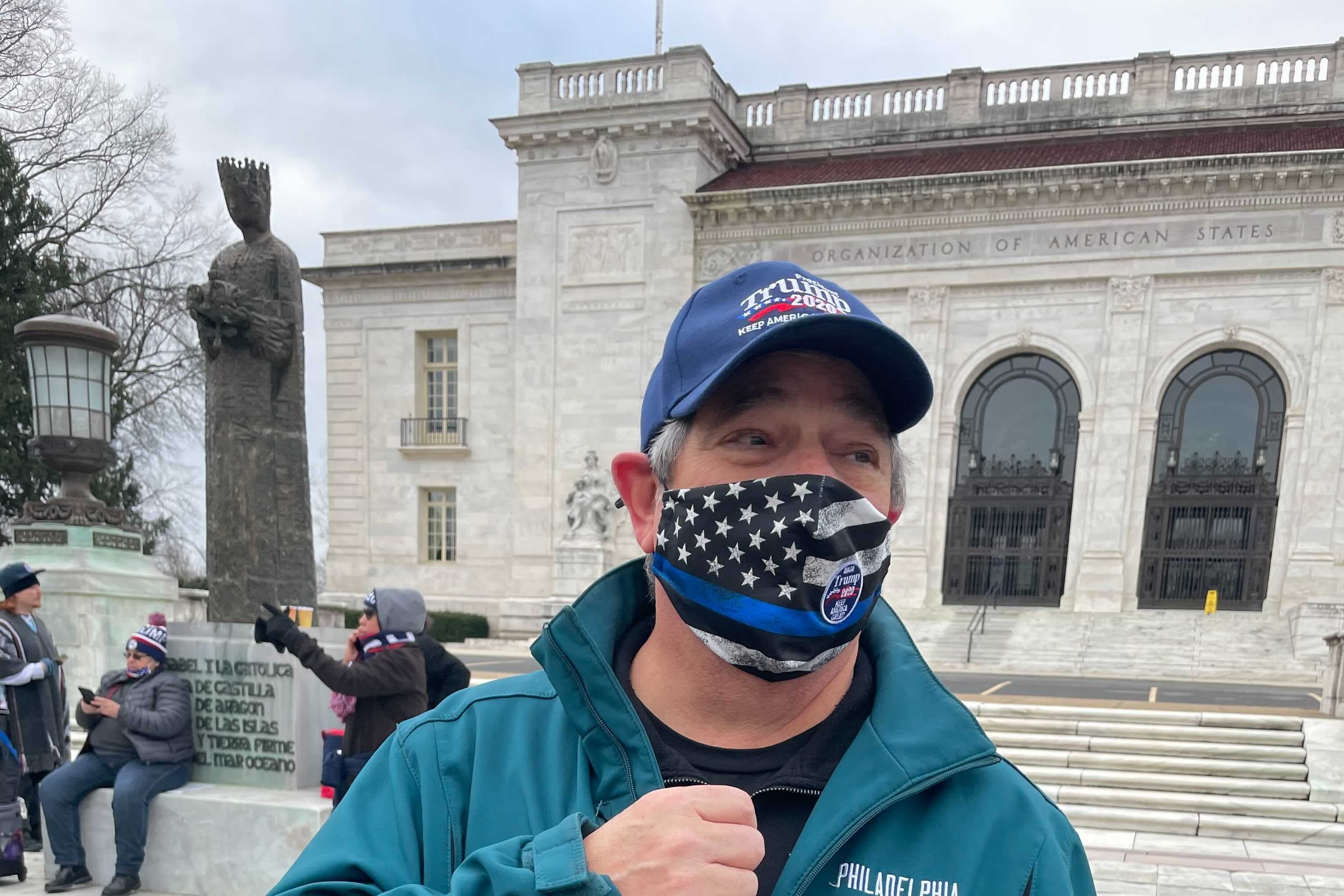A man in a Philadelphia Eagles jacket, wearing a Keep America Great mask and hat.