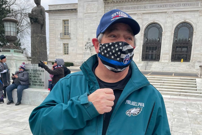 A man in a Philadelphia Eagles jacket, wearing a Keep America Great mask and hat.