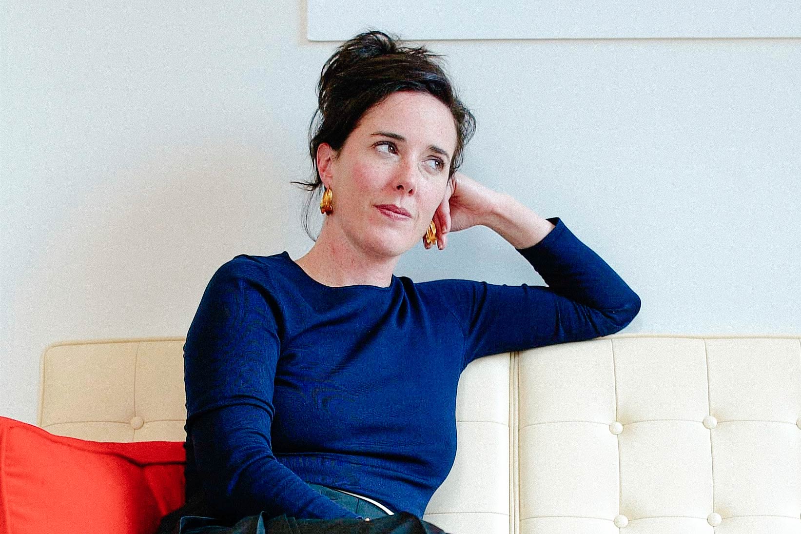 Kate Spade sits on a white leather couch.