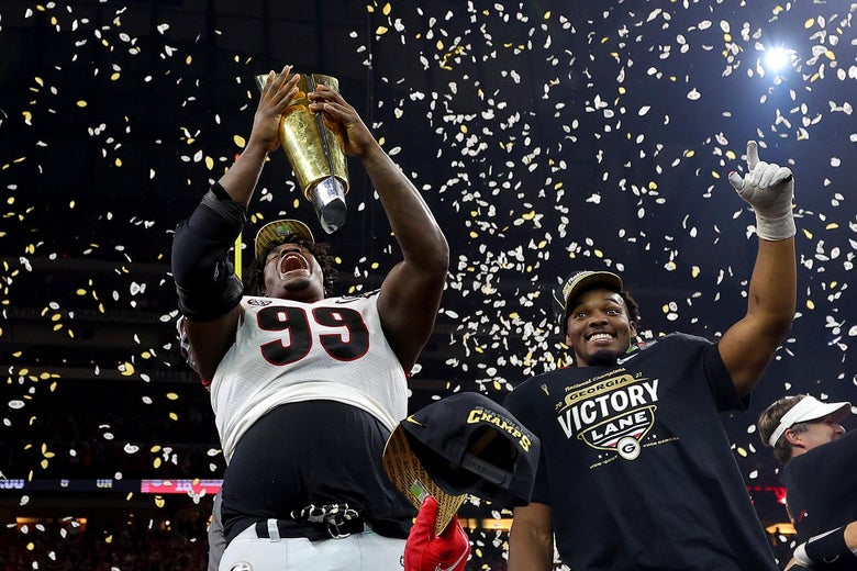 Davis holds the trophy skyward and screams as his teammate smiles and celebrates next to him in championship T-shirt and cap, confetti raining down on them both