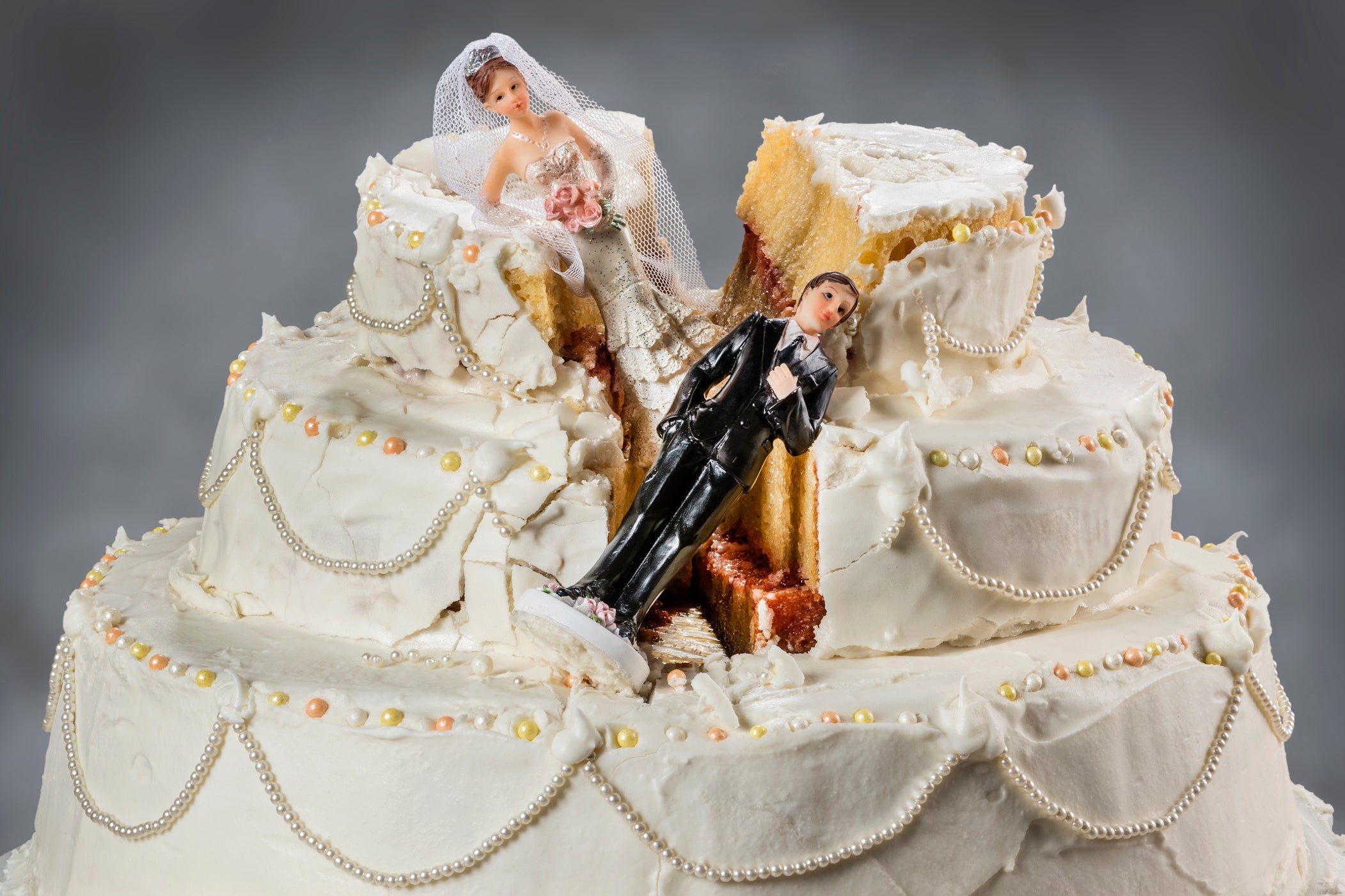 Bridge and groom figurines sink into a cut-up wedding cake.