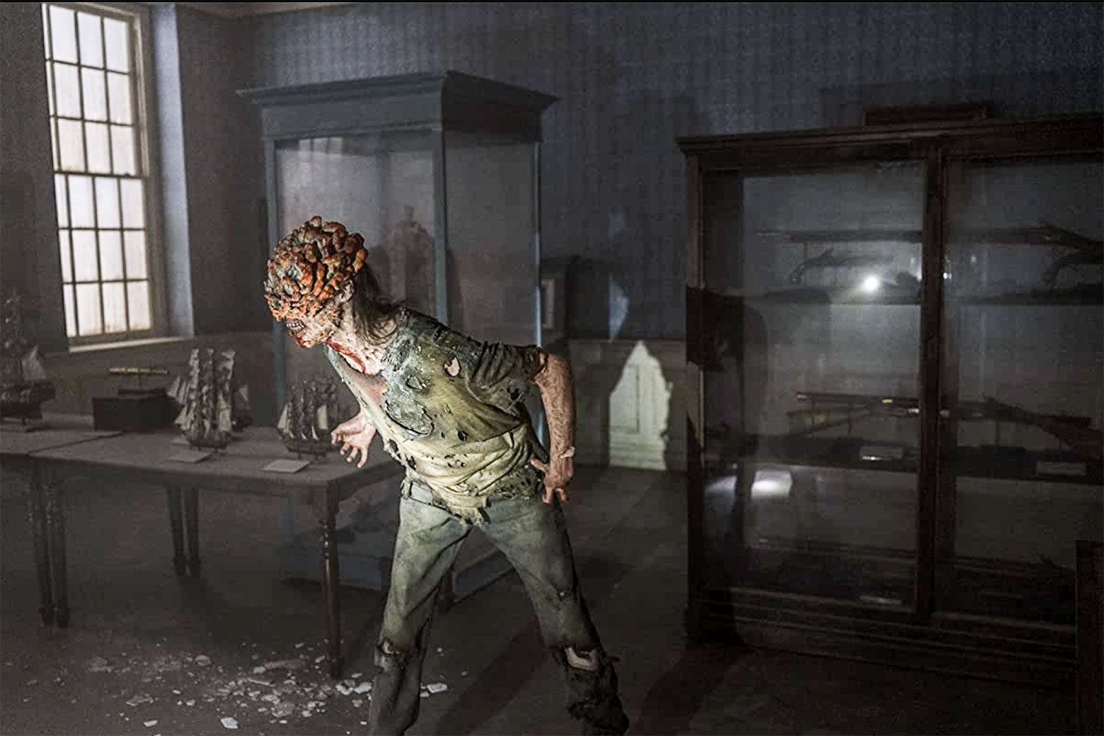 A zombie in the HBO show The Last of Us lunges in a dark room.