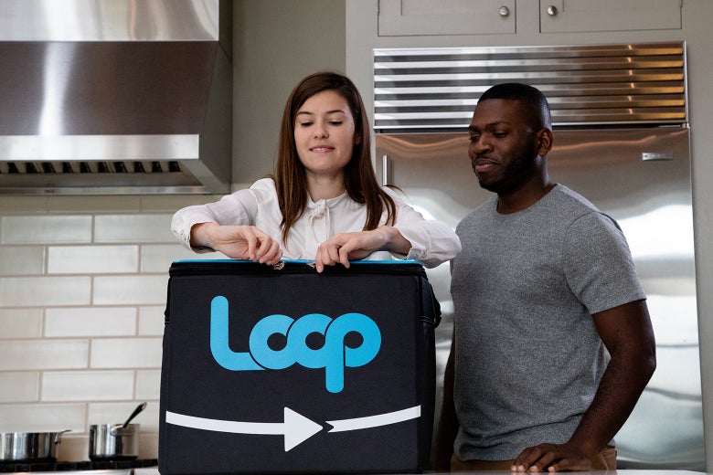 Image of two people standing next to a large reusable Loop brand container.