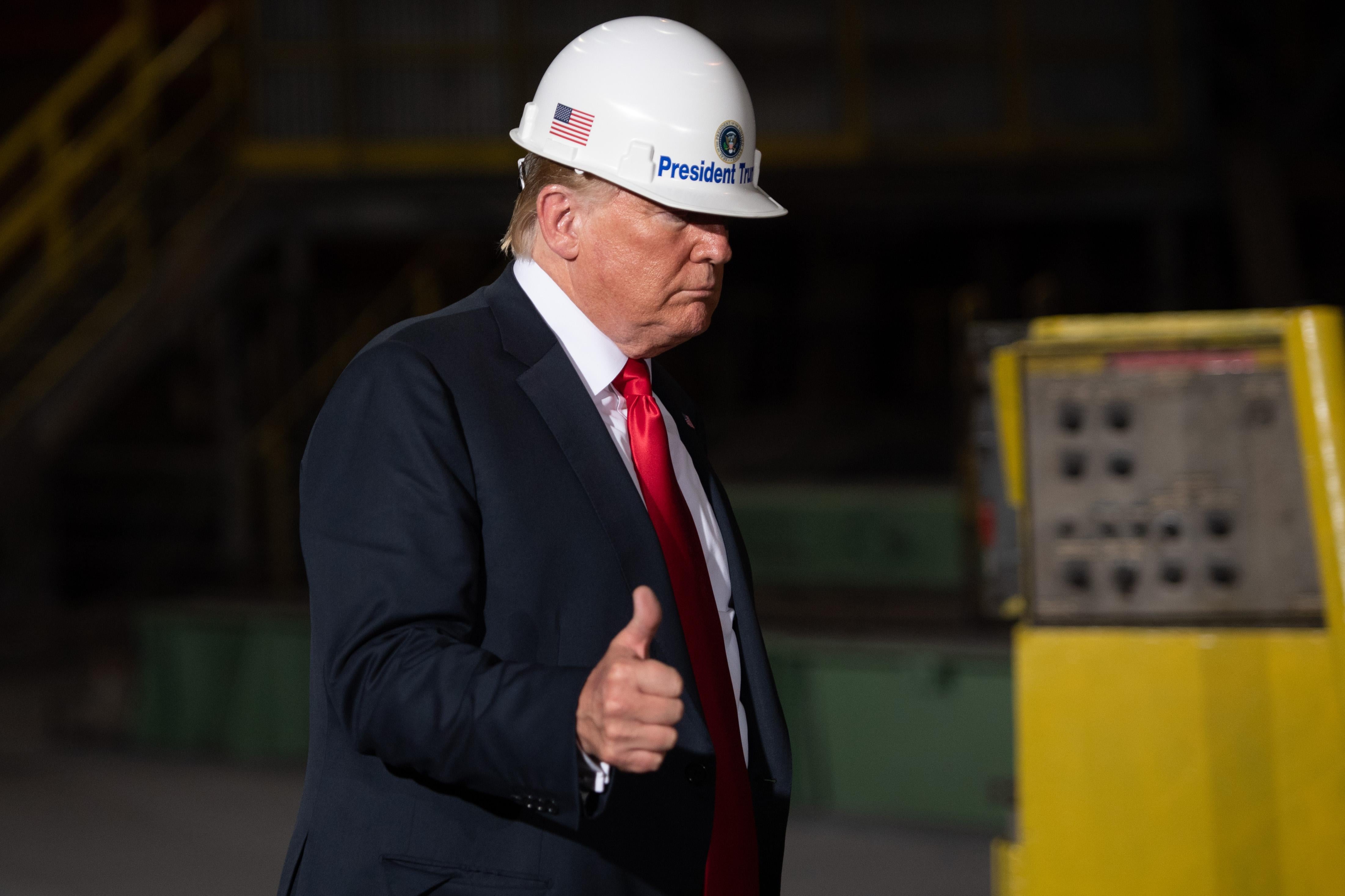 President Donald Trump wearing a hard hat, giving a thumbs up