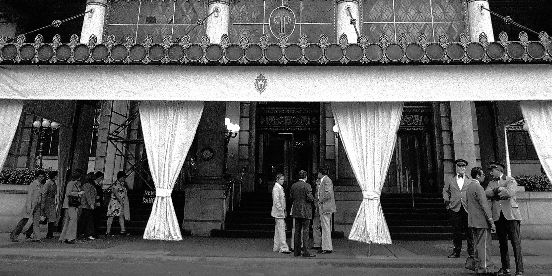 Three groups of people stand out front of the entrance of the Plaza Hotel in 1974.