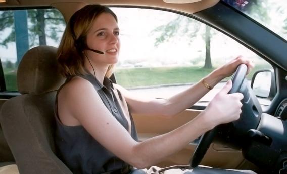 An unidentified woman uses a "hands-free" headset to make her driving easier and safer.