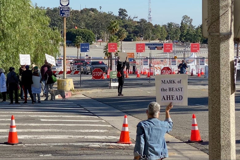 Protesters hold placards near entrance of vaccination center at Dodger Stadium in Los Angeles, California on January 30, 2021 in this still image obtained from a social media video. 