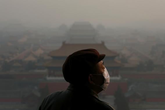 A tourist wearing the mask looks at the Forbidden City as pollution covers the city on January 16, 2013 in Beijing, China. 