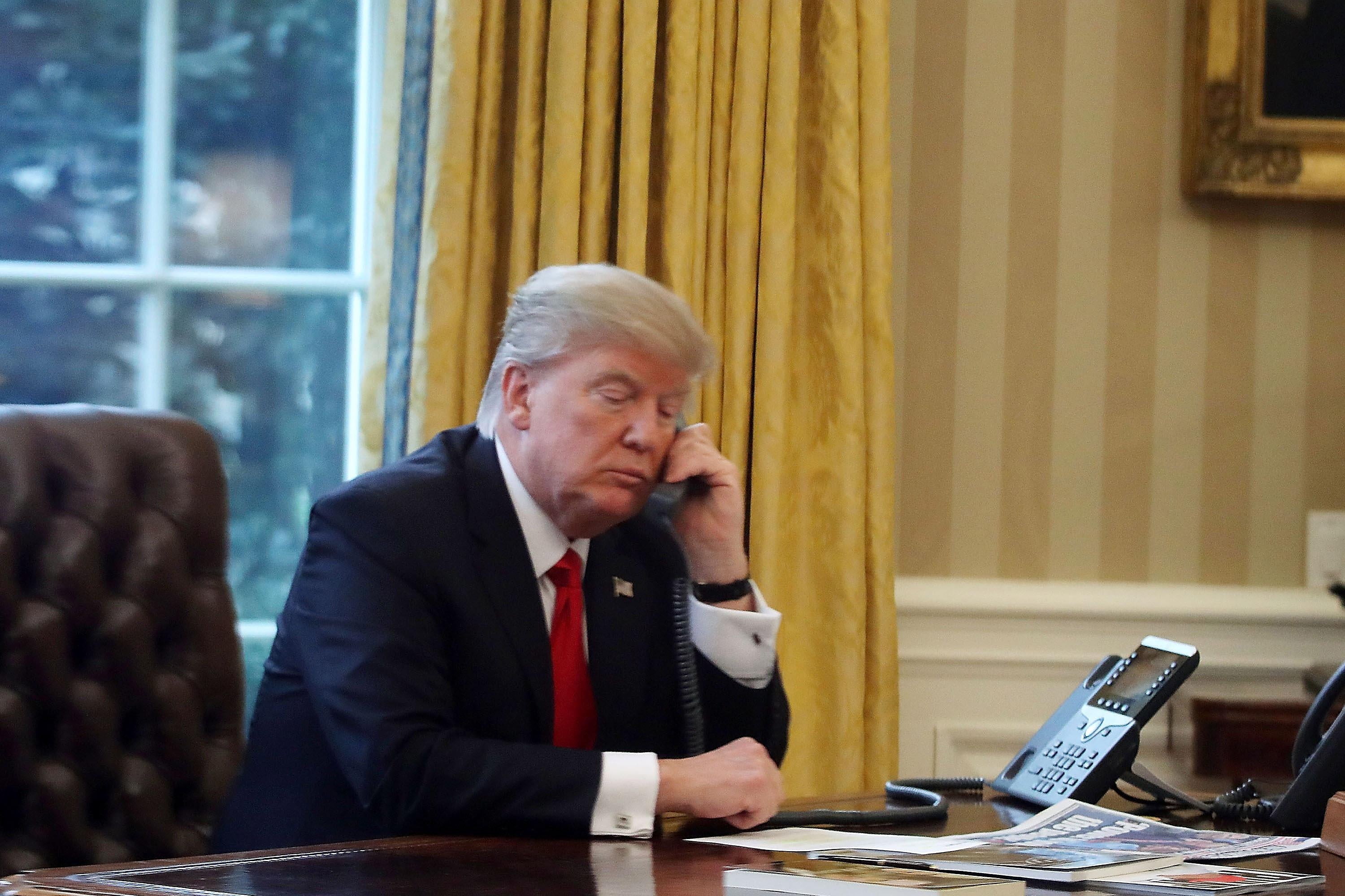 WASHINGTON, DC - JANUARY 29:  President Donald Trump is seen through a window speaking on the phone with King of Saudi Arabia, Salman bin Abd al-Aziz Al Saud, in the Oval Office of the White House, January 29, 2017 in Washington, DC. On Sunday, President Trump is making several phone calls with world leaders from the Oval Office.  (Photo by Mark Wilson/Getty Images)
