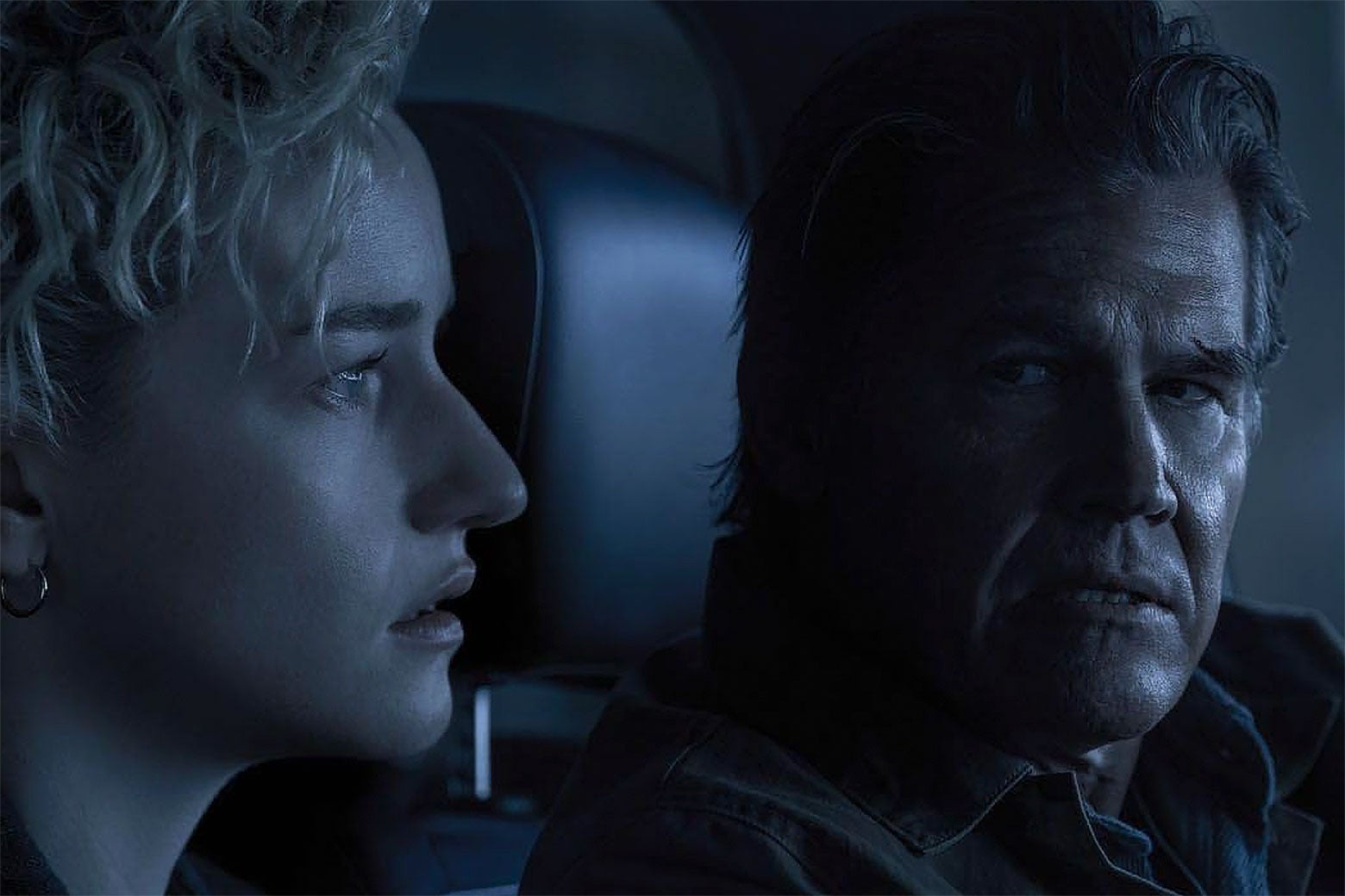 Ciddi bir Josh Brolin, arabanın sürücü koltuğunda, sıkıntılı Julia Garner'la konuşuyor.