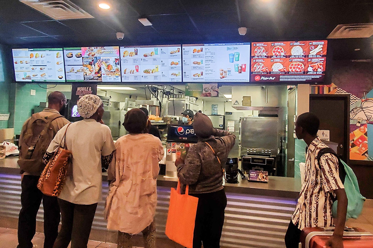 The menu and crowd inside a contemporary Pizza Hut-Taco Bell outpost in Queens, New York.
