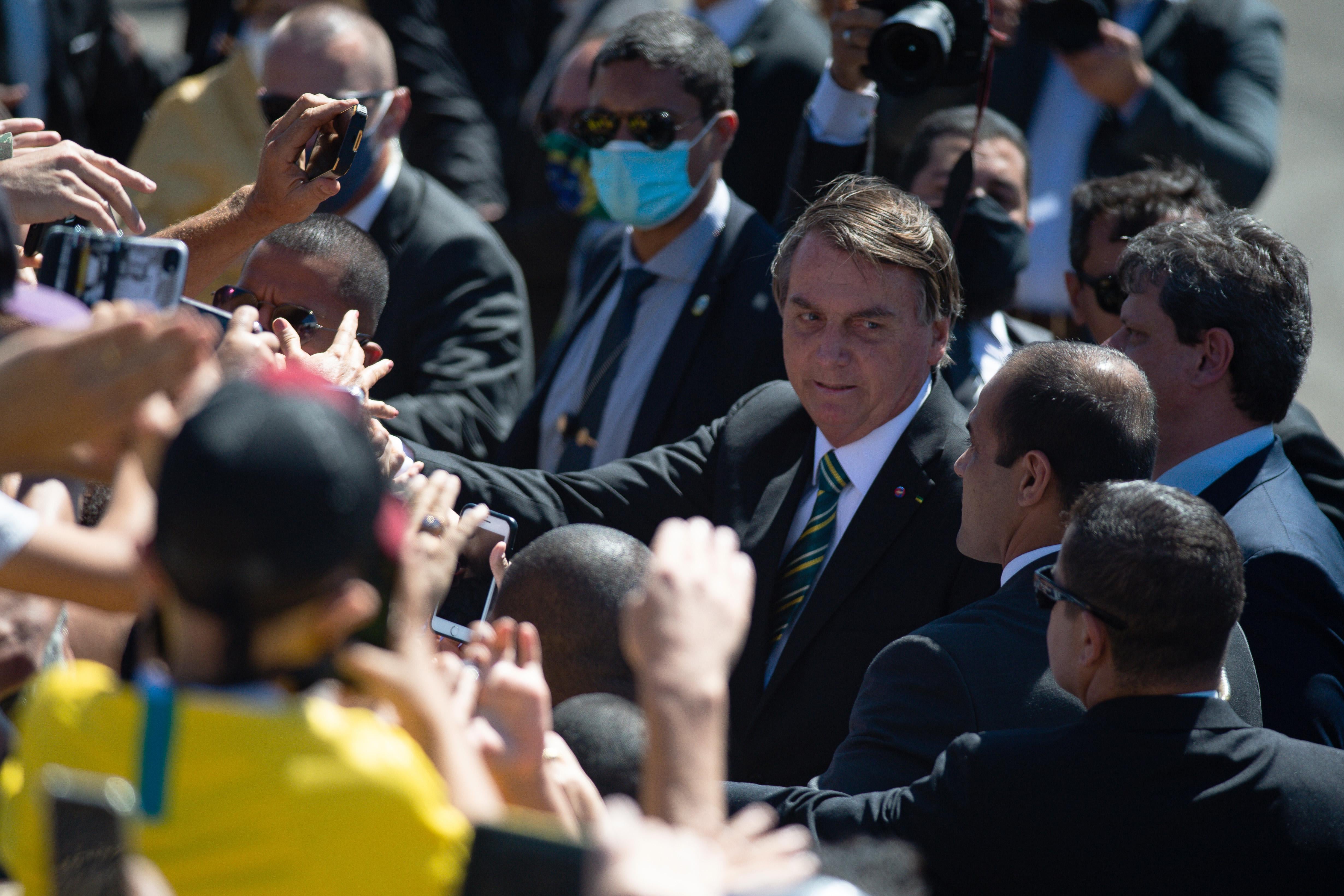 Bolsonaro, not wearing a mask, greets a crowd of his supporters