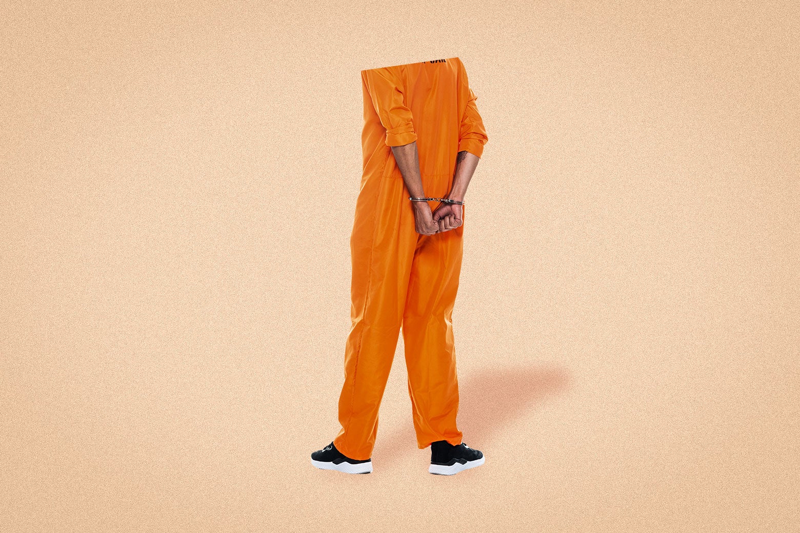 An incarcerated person wearing an orange jumpsuit and with his hands cuffed behind his back. 